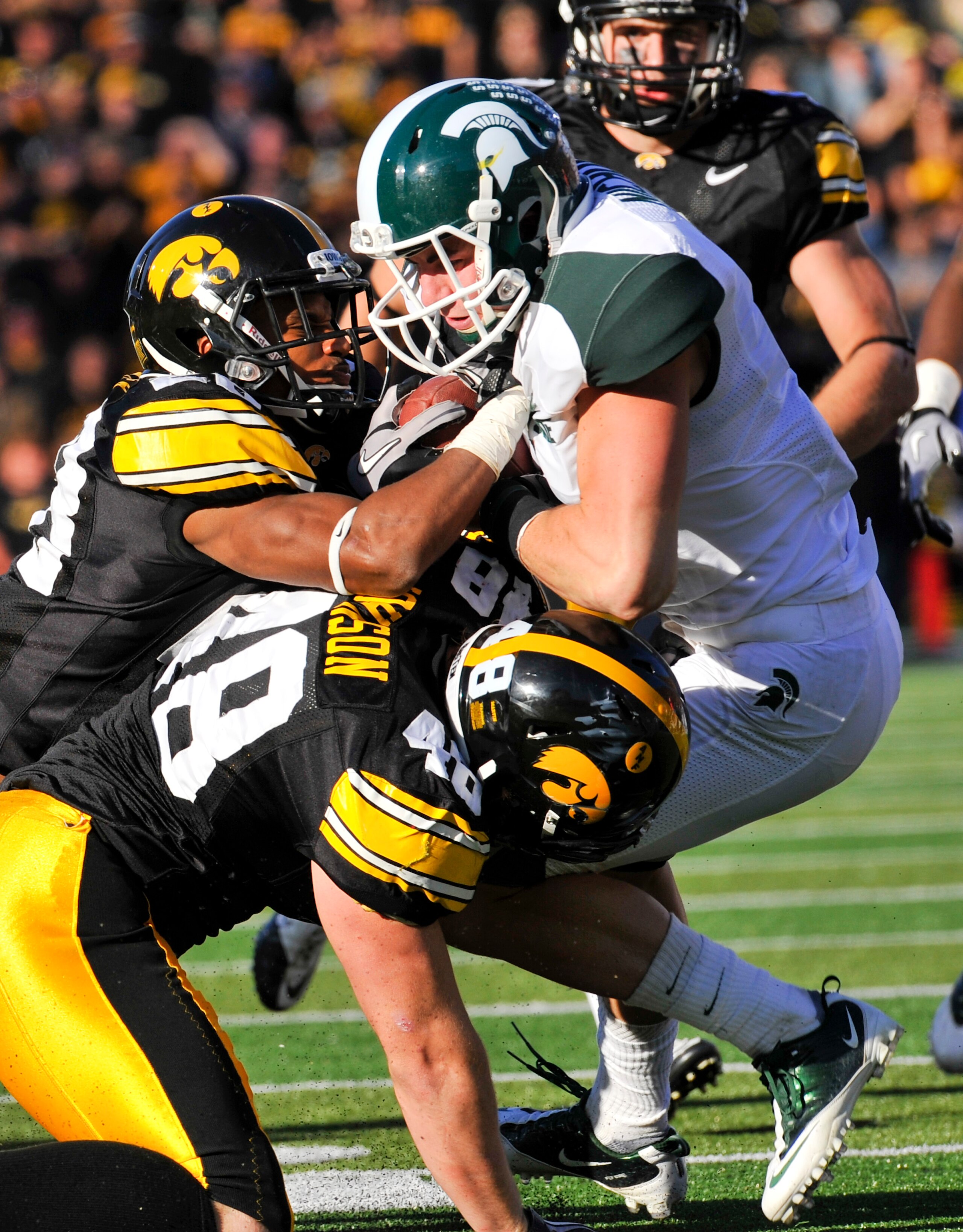 IOWA CITY, IA - OCTOBER 30: Line backer Troy Johnson #48 and defensive back Shaun Prater #28 of the University of Iowa Hawkeyes tackle wide receiver Keith Nichol #7 of the Michigan State Spartans during the first half of play at Kinnick Stadium on October
