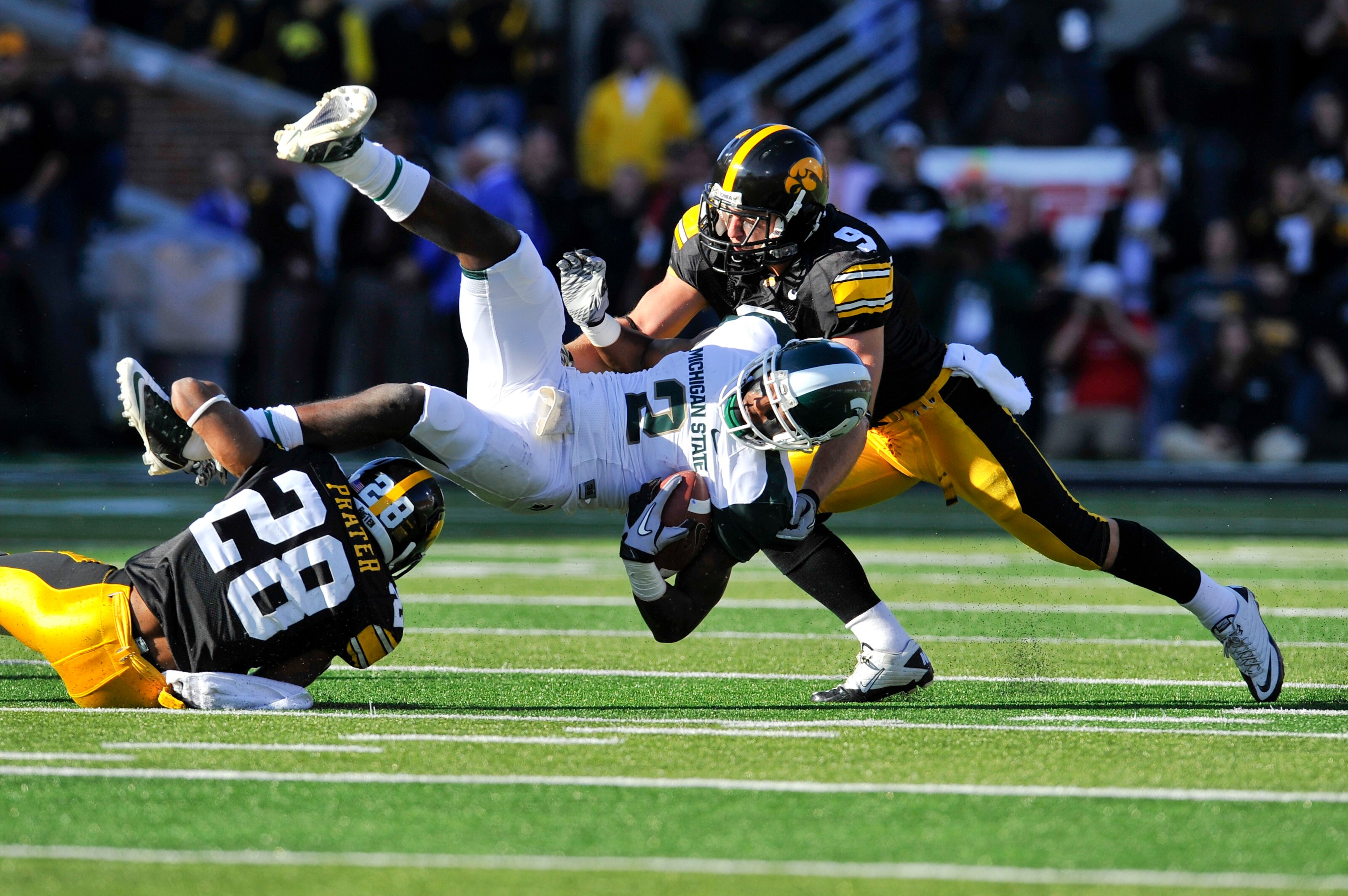 IOWA CITY, IA - OCTOBER 30: Wide receiver Mark Bell #2 of the Michigan State Spartans is tackled by defensive back Tyler Sash #9 of the University of Iowa Hawkeyes and his teammate defensive back Shaun Prater #28 as he rushes for yards during the first ha