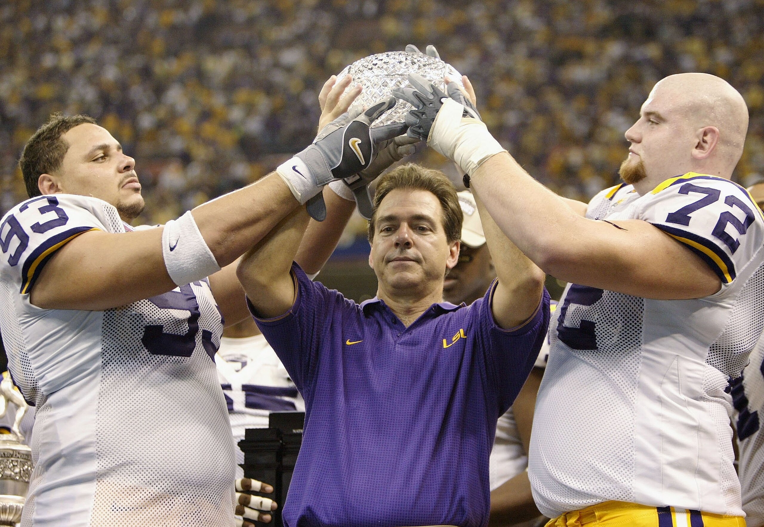 NEW ORLEANS - JANUARY 4:  Head coach Nick Saban of LSU holds up the National championship trophy with his players Chad Lavalais #93 and Stephen Peterman #72 after defeating Oklahoma 21-14 to win the National Championship at the Nokia Sugar Bowl on January