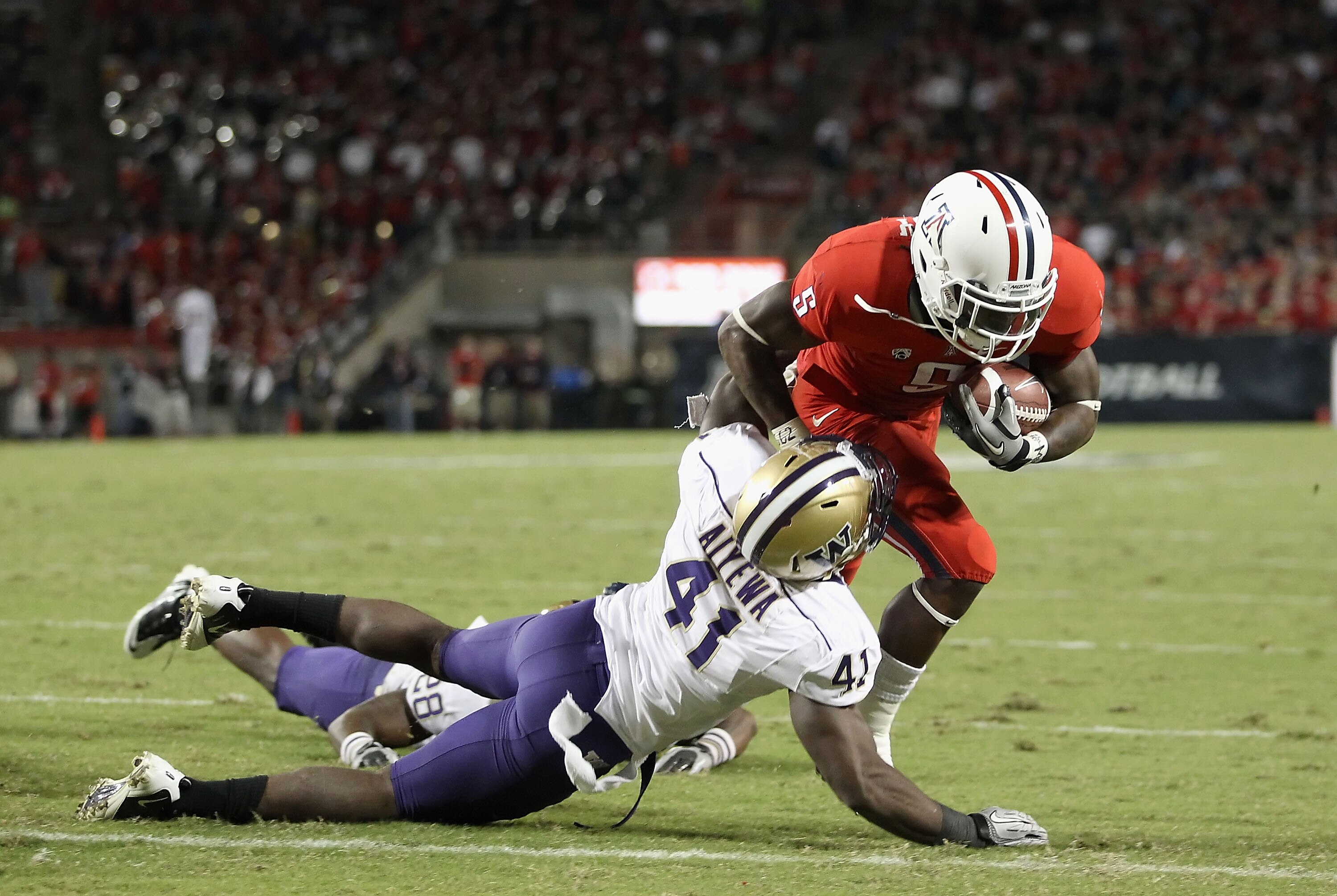 TUCSON, AZ - OCTOBER 23:  Runningback Nic Grigsby #5 of the Arizona Wildcats scores a 4 yard rushing touchdown agianst Victor Aiyewa #41 of the Washington Huskies during the third quarter of the college football game at Arizona Stadium on October 23, 2010