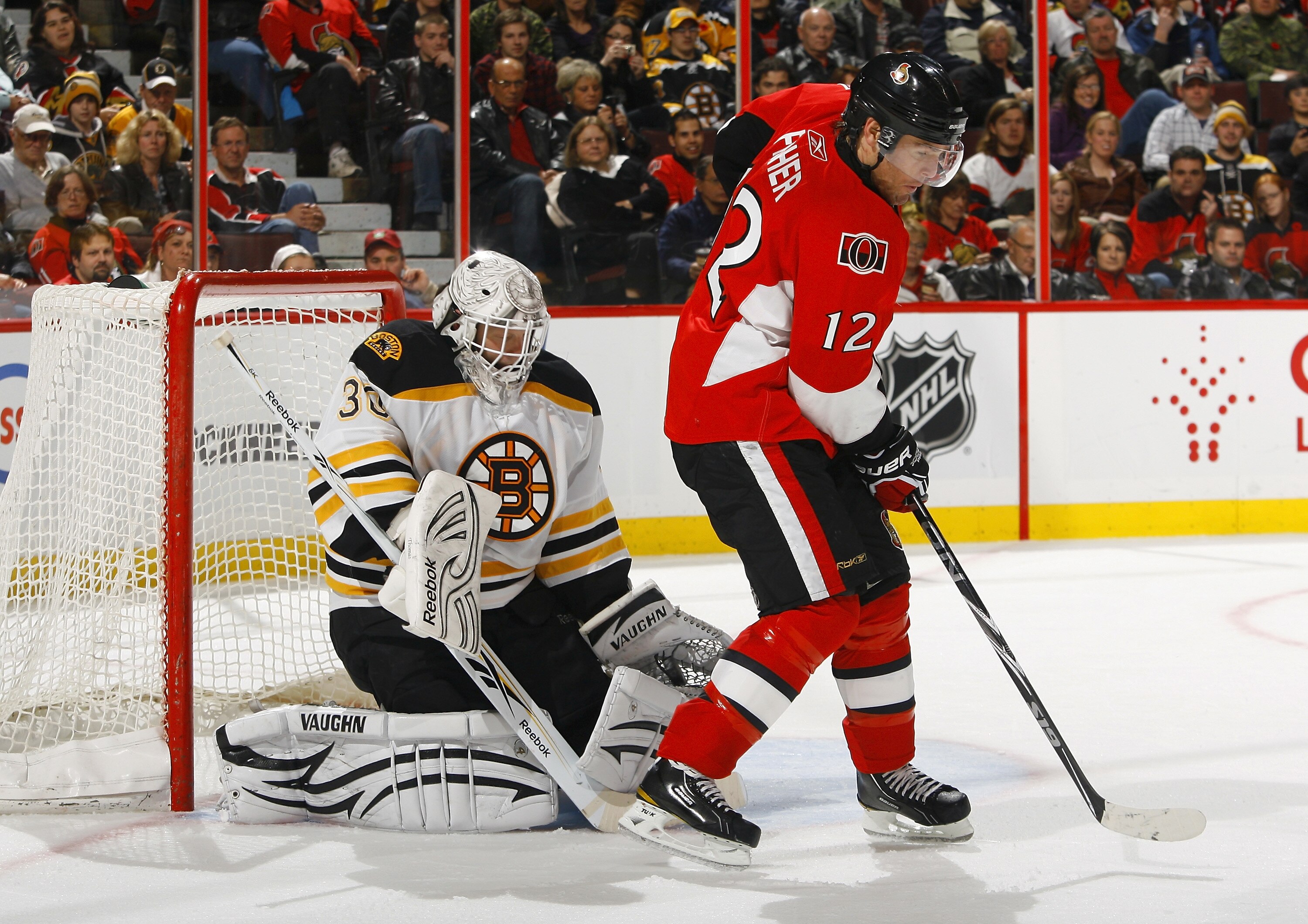 OTTAWA, ON - OCTOBER 30:  Tim Thomas #30 of the Boston Bruins makes a big glove save with Mike Fisher #12 of the Ottawa Senators providing a screen at the top of the crease during a game at Scotiabank Place on October 30, 2010 in Ottawa, Ontario, Canada.