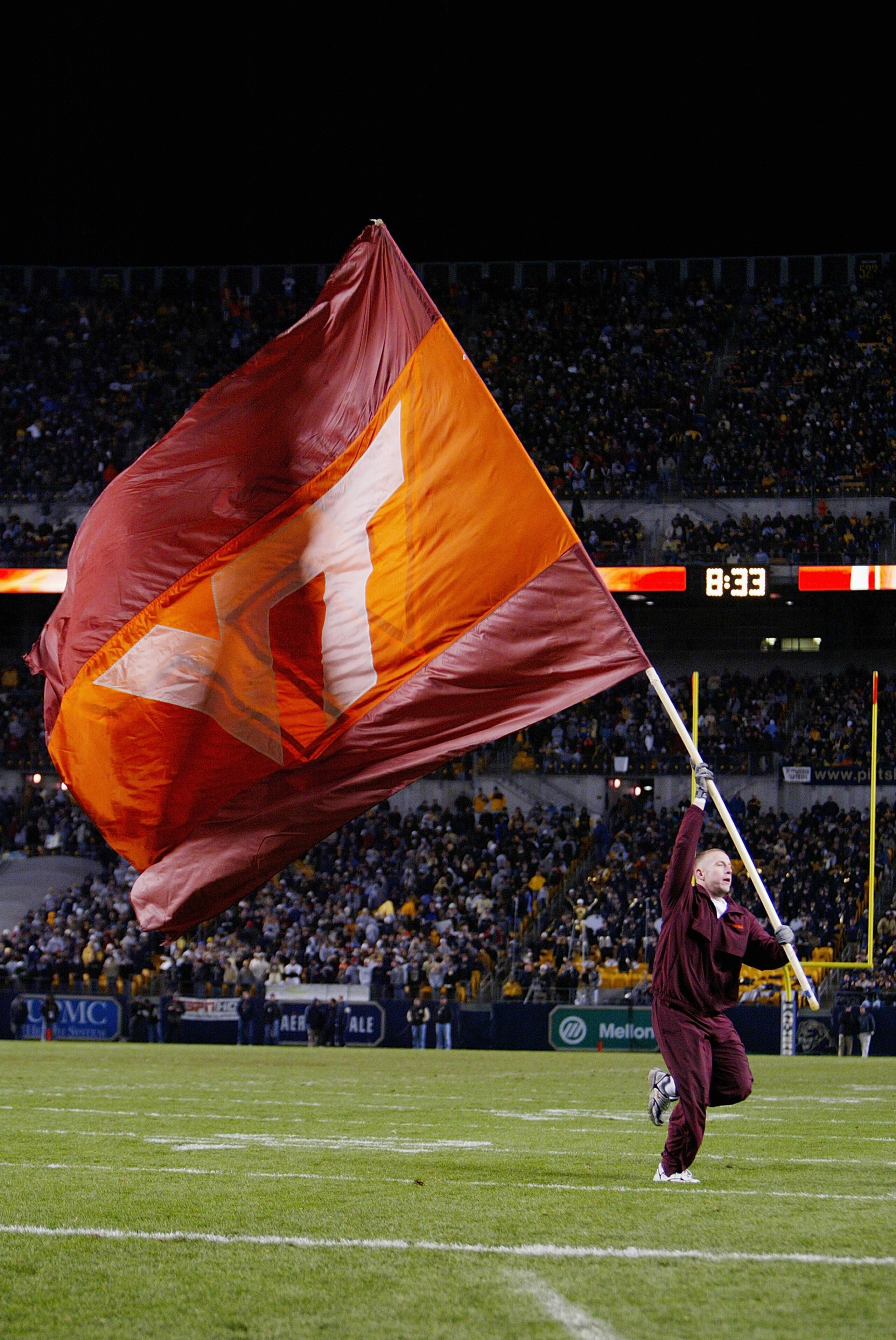 PITTSBURGH - NOVEMBER 8:  A member of the Virginia Tech Hokies cheerleading team runs out on the field with the team flag during the game against the Pittsburgh Panthers on November 8, 2003 at Heinz Field in Pittsburgh, Pennsylvania. The Panthers defeated