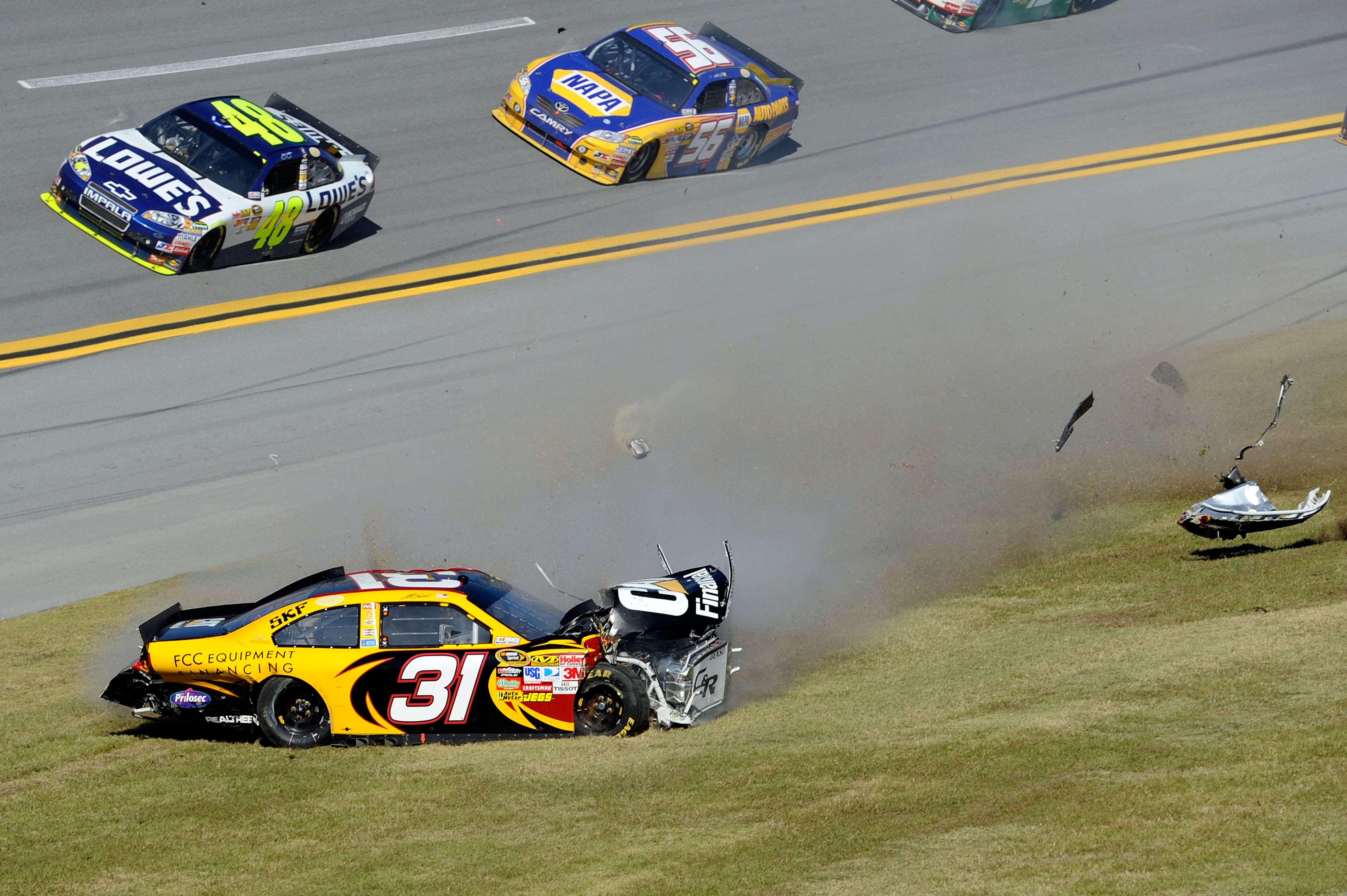 TALLADEGA, AL - OCTOBER 31:  Jimmie Johnson, driver of the #48 Lowe's Chevrolet,  and Martin Truex Jr., driver of the #56 NAPA Toyota, pass by Jeff Burton, driver of the #31 Cat Financial Chevrolet, spins out on the grass after hitting the wall in the NAS