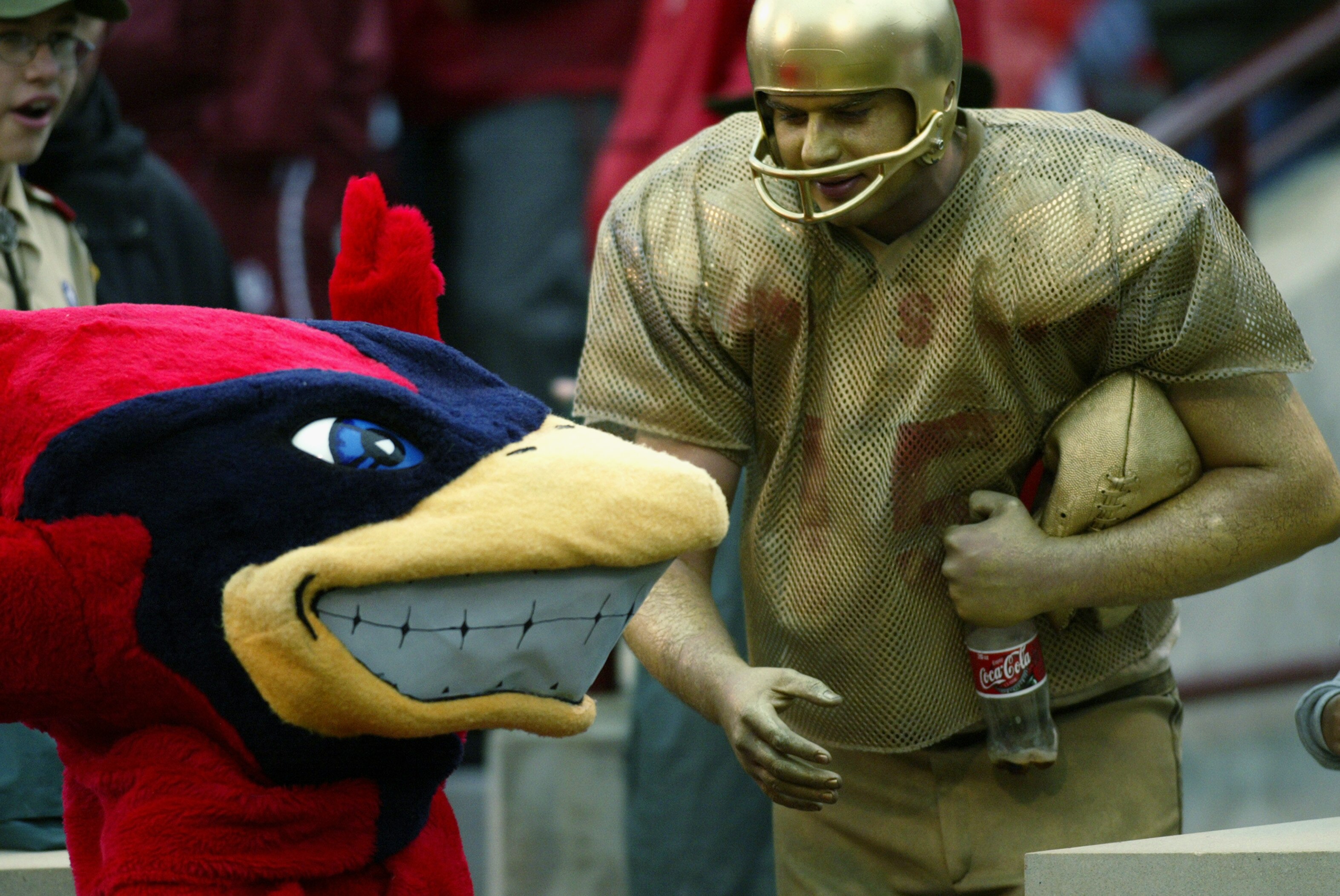 NORMAN, OK - OCTOBER 19:  A fan painted gold plays around with the Sooner mascot during the game between the Iowa State Cyclones and the Oklahoma Sooners on October 19, 2002 at Gaylord Family-Oklahoma Memorial Stadium in Norman, Oklahoma.   (Photo by Rona