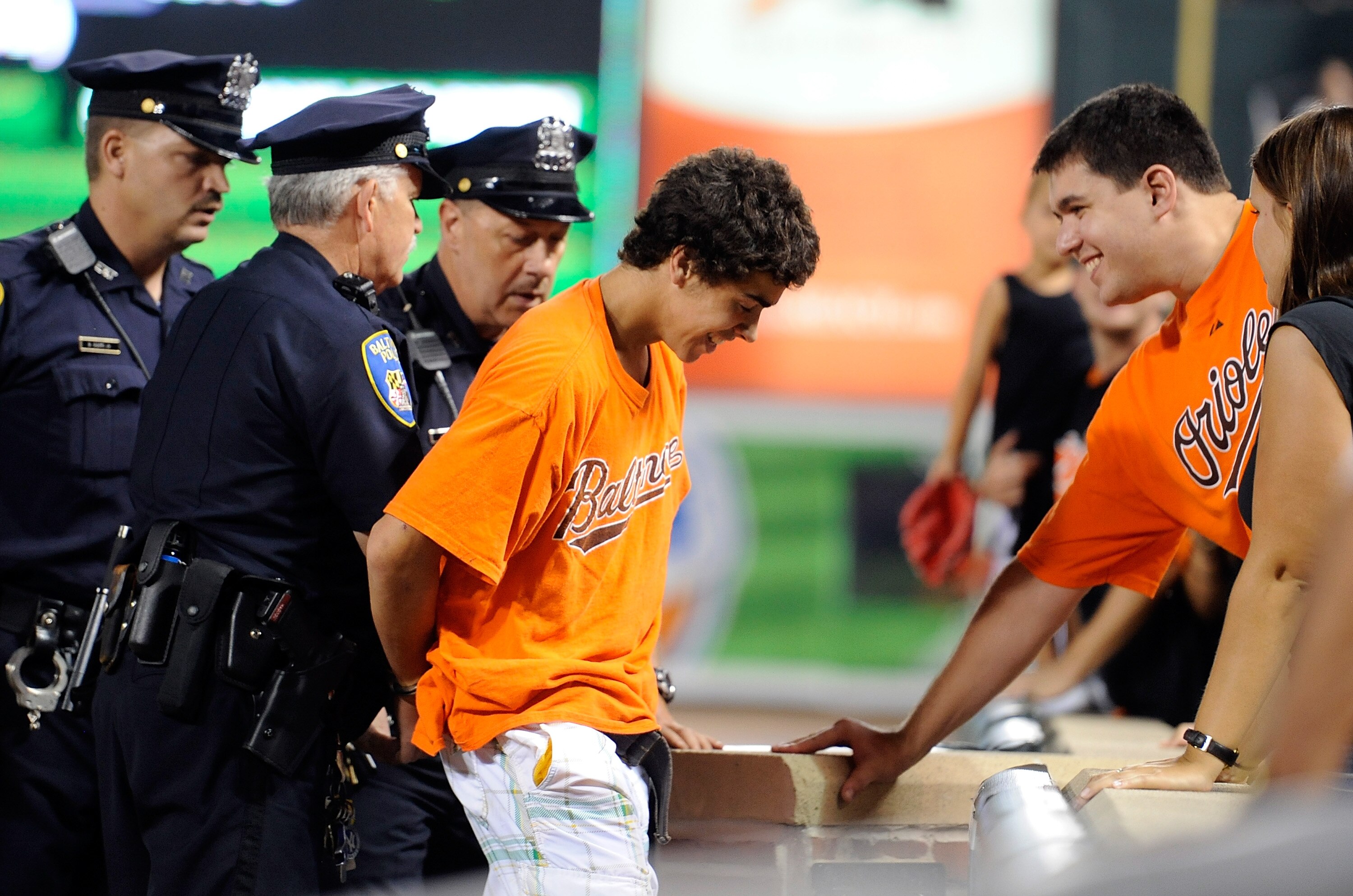 BALTIMORE - JULY 22:  A fan is escorted off the field by the police during the game between the Minnesota Twins and the Baltimore Orioles at Camden Yards on July 22, 2010 in Baltimore, Maryland.  (Photo by Greg Fiume/Getty Images)