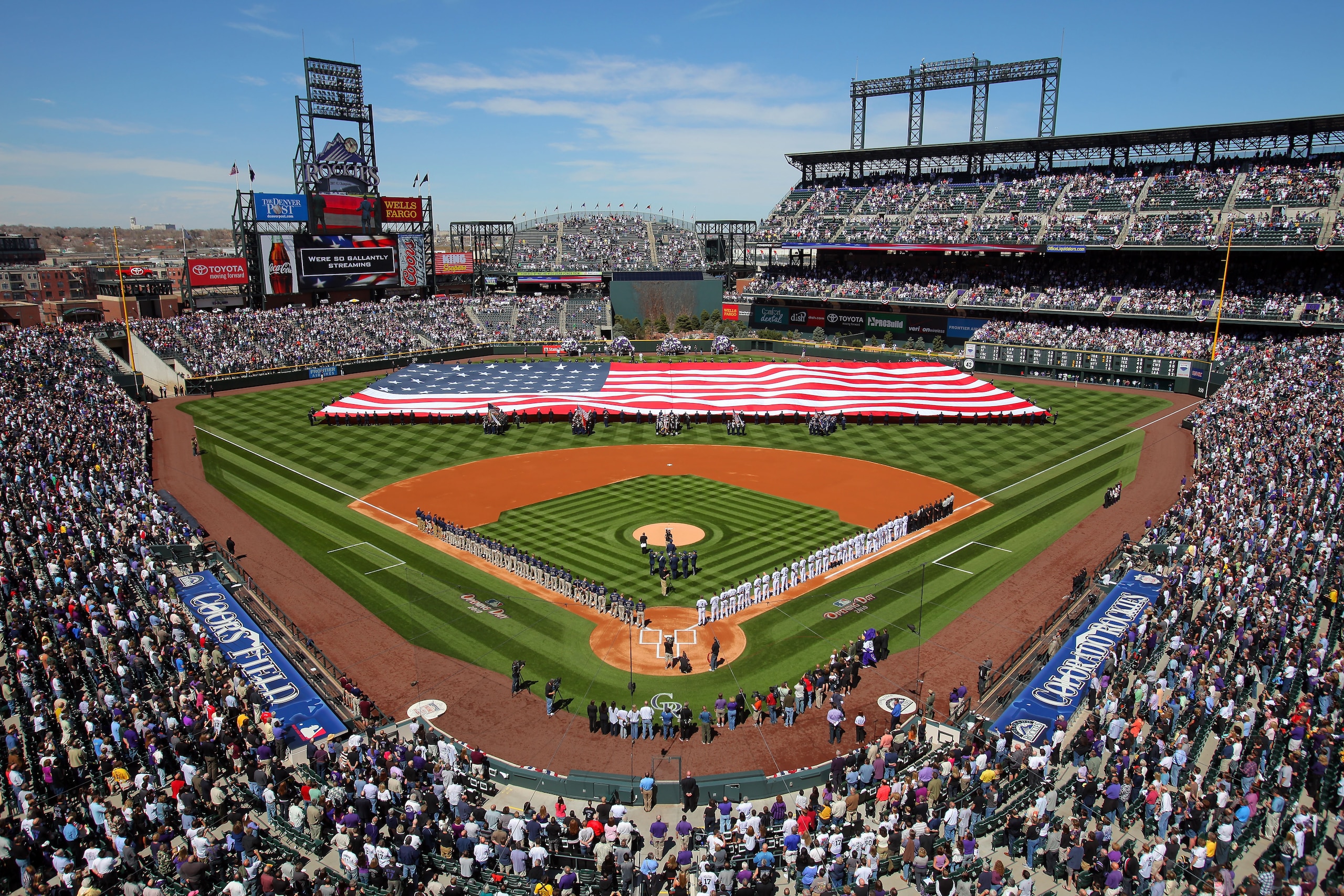 DENVER - APRIL 09:  Players and fans observe the national anthem as the stars and stripes is presented by members of the US military as the Colorado Rockies host the San Diego Padres during MLB action on Opening Day at Coors Field on April 9, 2010 in Denv