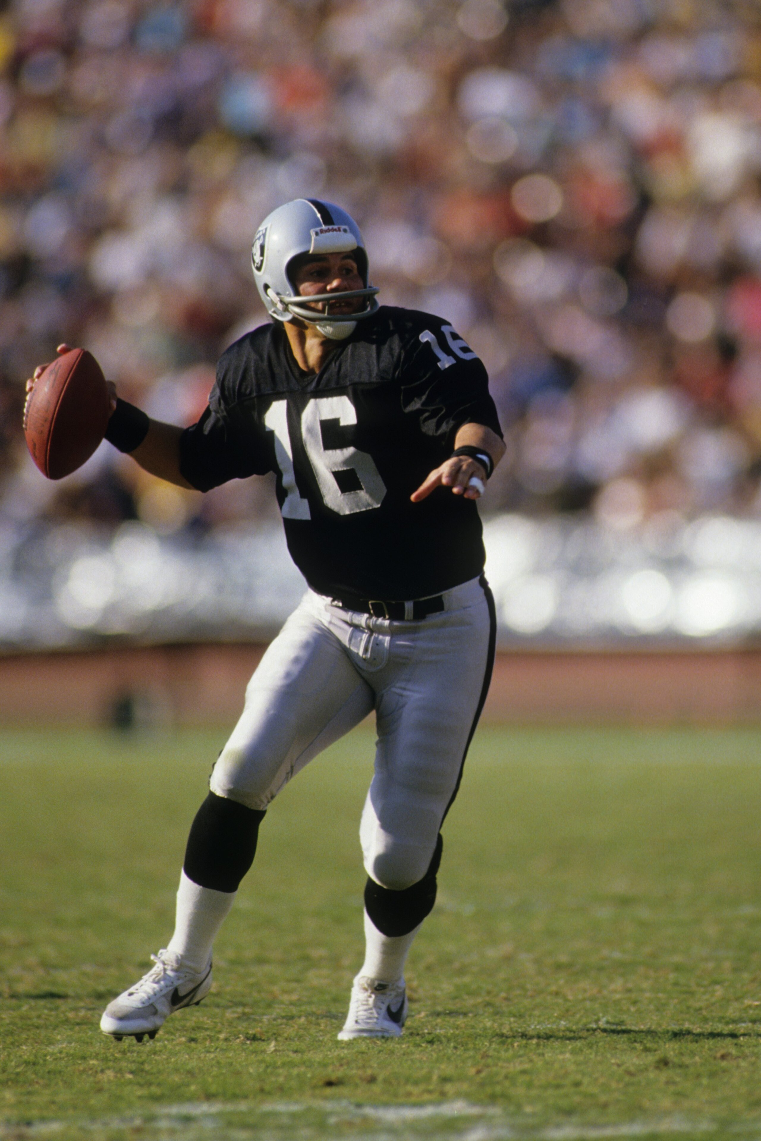LOS ANGELES - NOVEMBER 30:  Quarterback Jim Plunkett #16 of the Los Angeles Raiders drops back to pass during the game against the Philadelphia Eagles at the Los Angeles Memorial Coliseum on November 30, 1986 in Los Angeles, California.  The Eagles won 33