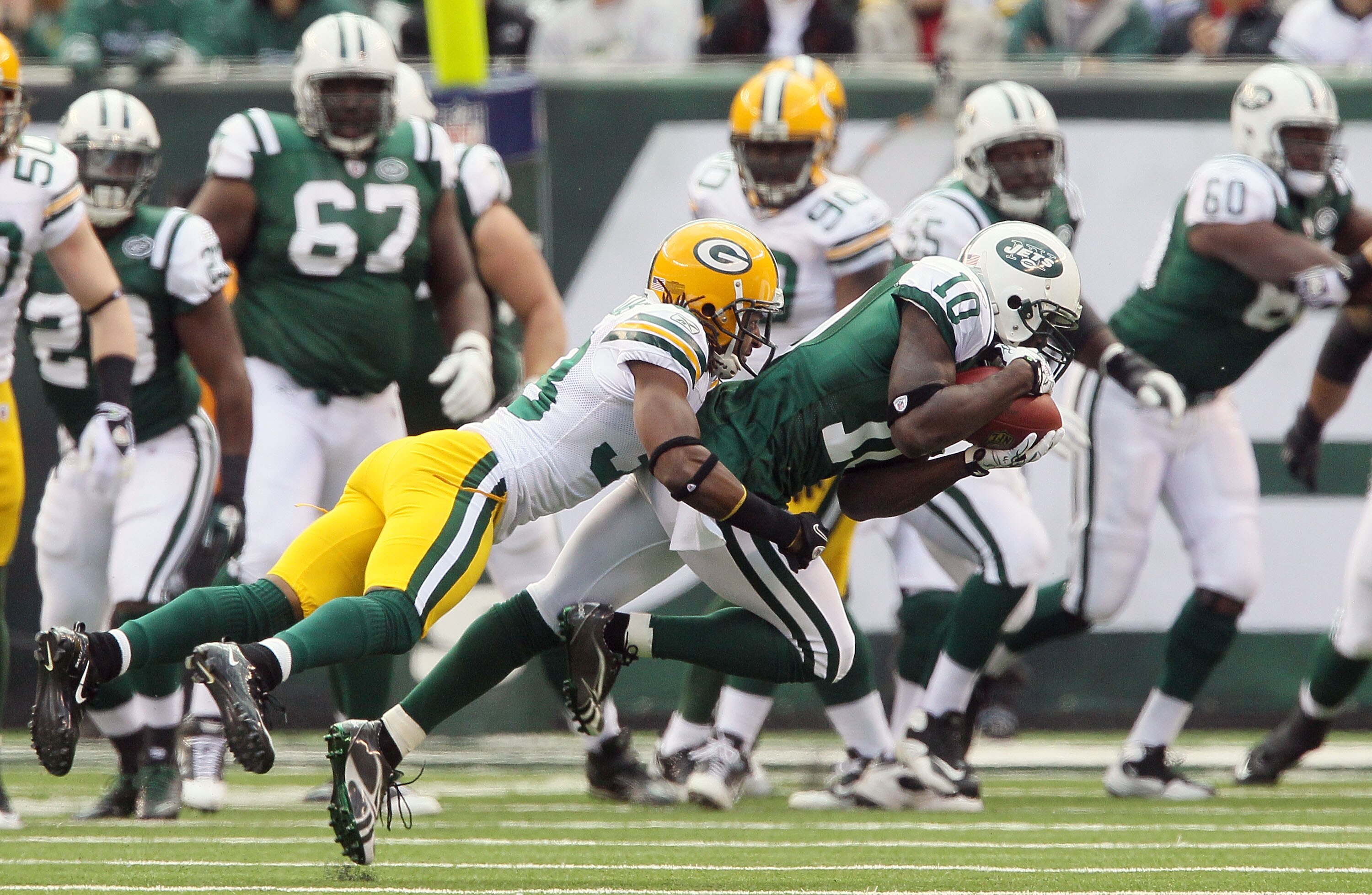 EAST RUTHERFORD, NJ - OCTOBER 31:  Santonio Holmes #10 of the New York Jets hauls in a pass ahead of Tramon Williams #38 of the Green Bay Packers on October 31, 2010 at the New Meadowlands Stadium in East Rutherford, New Jersey.  (Photo by Jim McIsaac/Get
