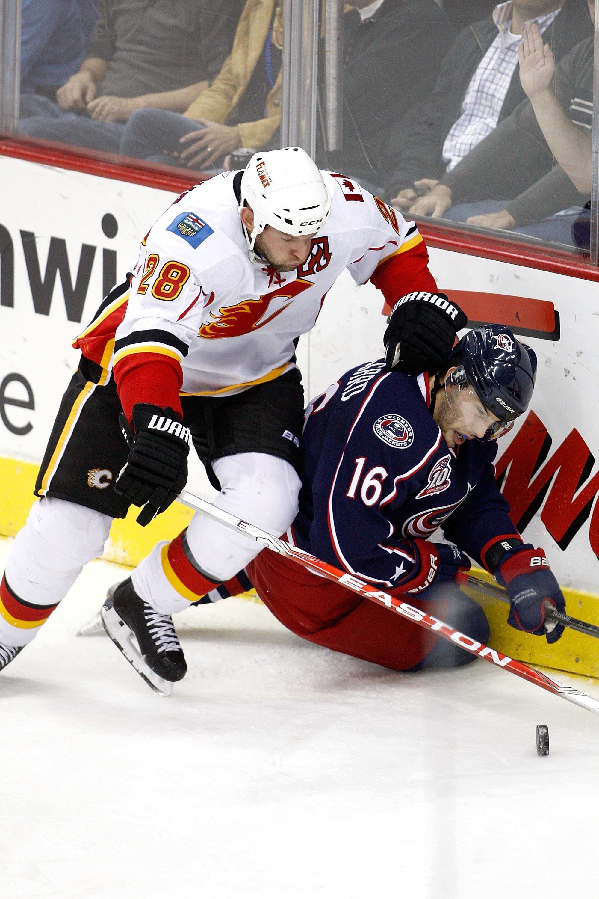 COLUMBUS, OH - OCTOBER 22:  Robyn Regehr #28 of the Calgary Flames knocks Derick Brassard #16 of the Columbus Blue Jackets to the ice while chasing after a loose puck during the third period on October 22, 2010 at Nationwide Arena in Columbus, Ohio.  Calg
