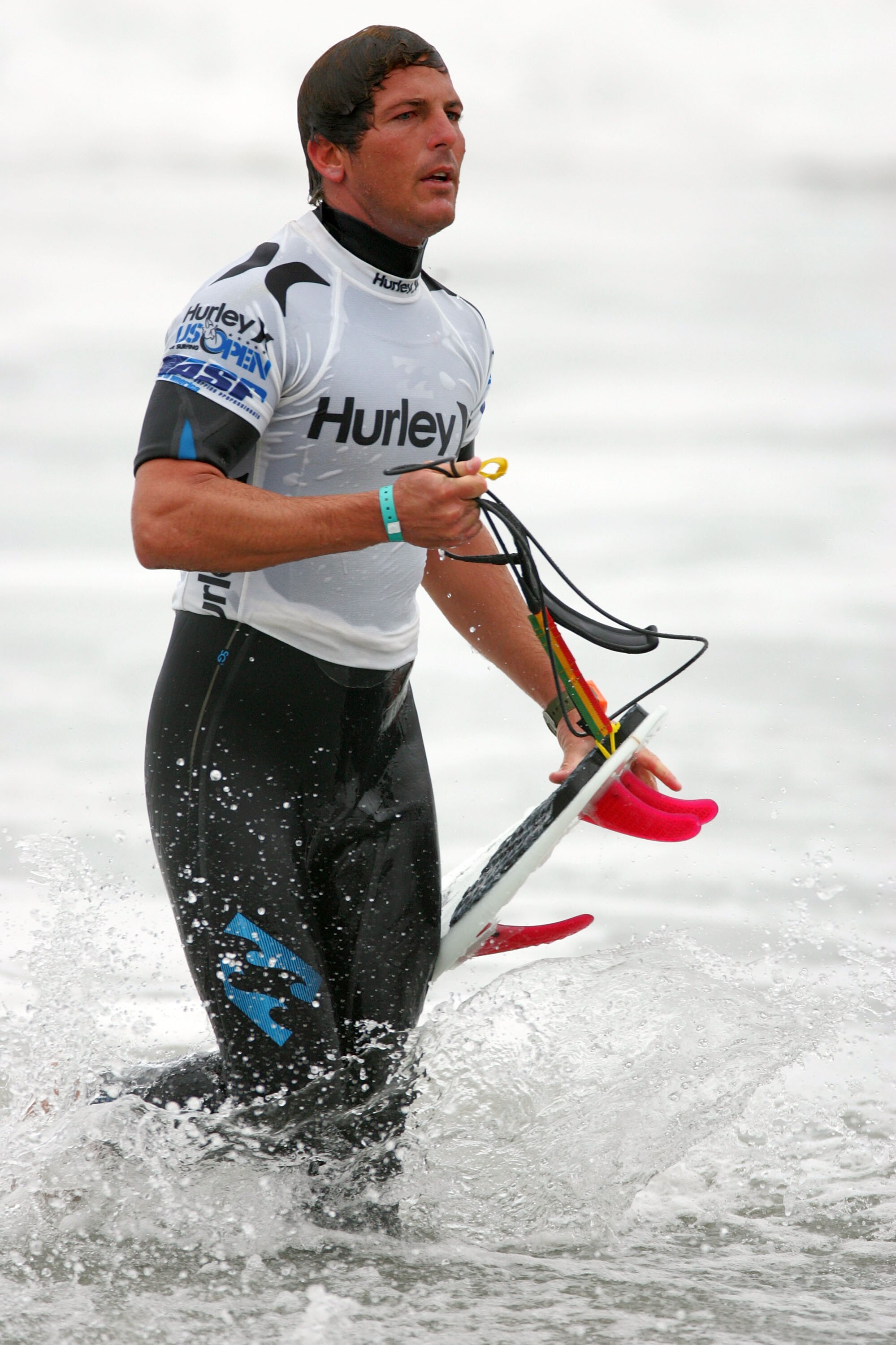 HUNTINGTON BEACH, CA - JULY 24:  Andy Irons (Hawaii) walks through the shorebreak with a broken fin still on his board after his morning heat during the 2009 Hurley U.S. Open of Surfing on July 24, 2009 in Huntington Beach, California.  (Photo by Victor D