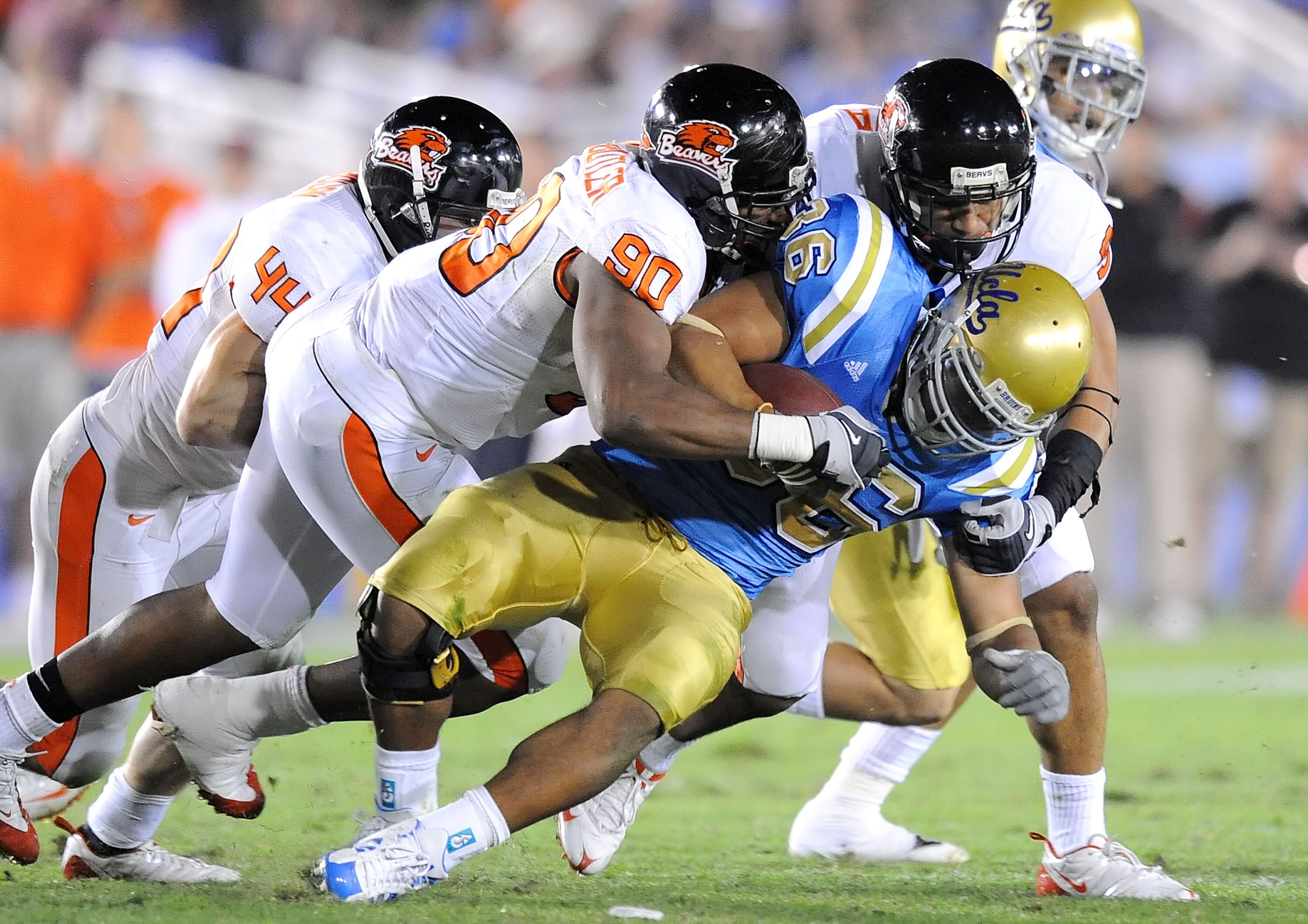 PASADENA, CA - NOVEMBER 08:   (L-R)Victor Butler #90 and Al Afalava #9 of the Oregon State Beavers tackle Kahlil Bell #36 of the UCLA Bruins at the Pasadena Rose Bowl on November 8, 2008 in Pasadena, California.  (Photo by Lisa Blumenfeld/Getty Images)