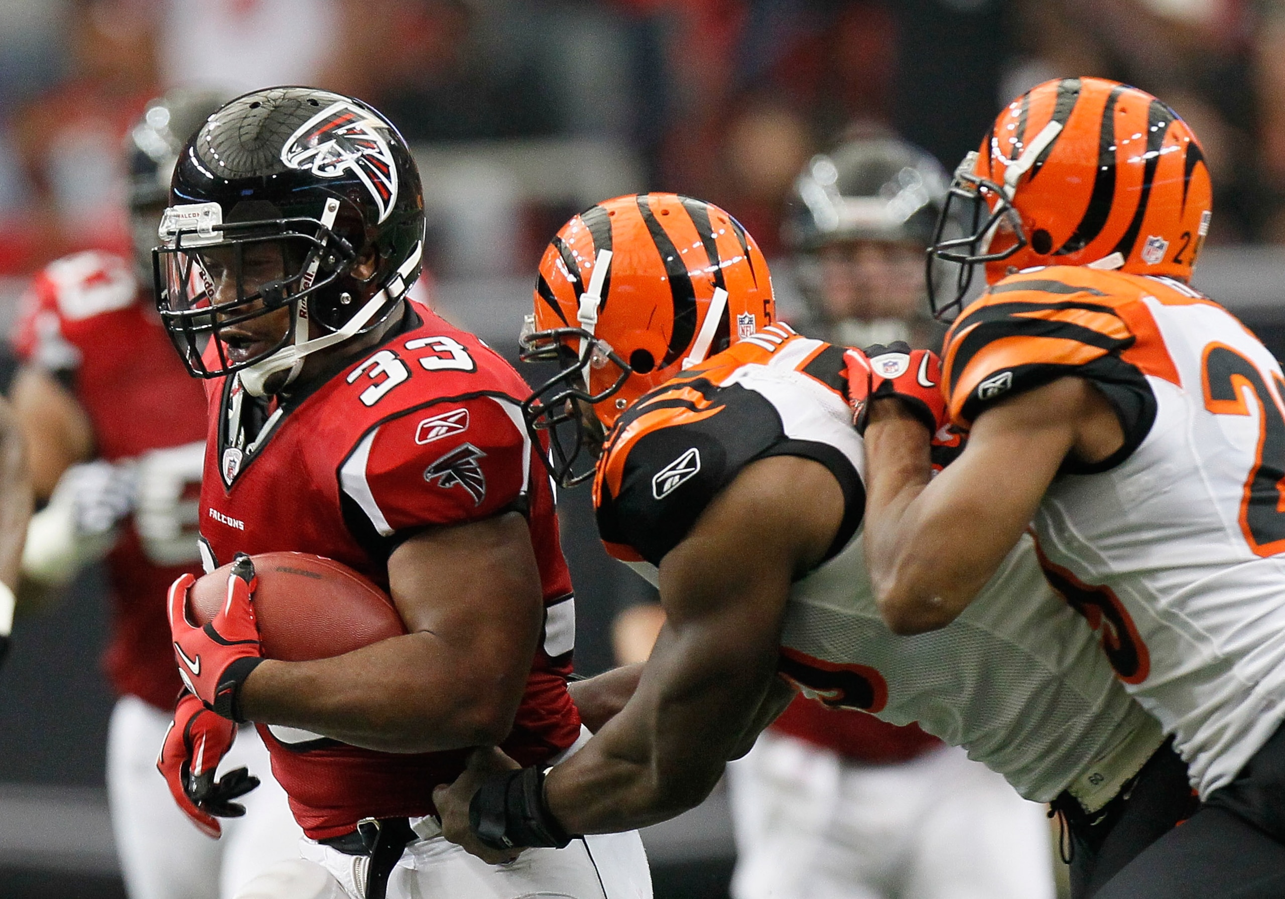 ATLANTA - OCTOBER 24:  Michael Turner #33 of the Atlanta Falcons rushes away from Keith Rivers #55 and Leon Hall #29 of the Cincinnati Bengals at Georgia Dome on October 24, 2010 in Atlanta, Georgia.  (Photo by Kevin C. Cox/Getty Images)