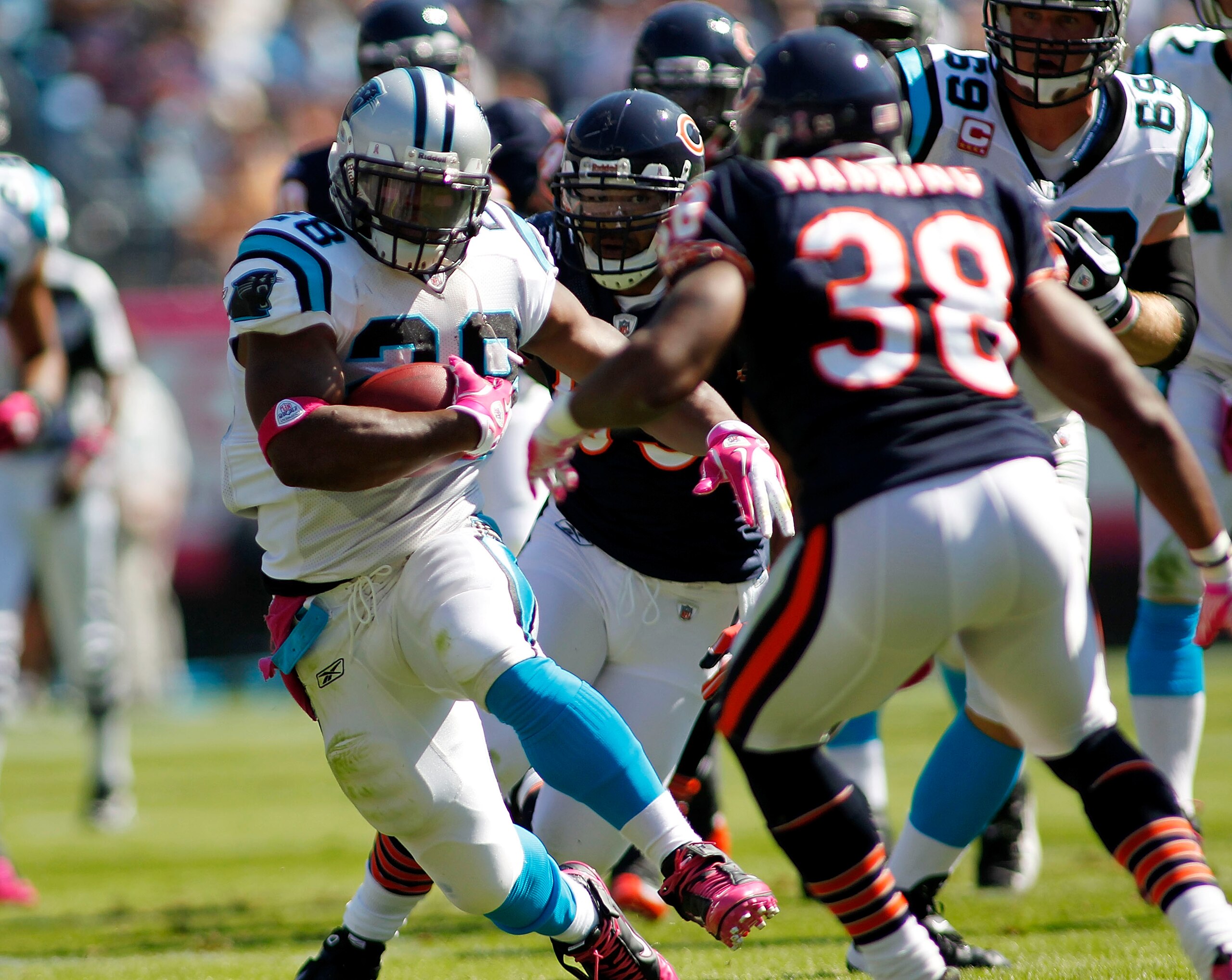 CHARLOTTE, NC - OCTOBER 10: Running back Jonathan Stewart #28 of the Carolina Panthers runs with the ball as defensive end Julius Peppers #90 and safety Danieal Manning #38 of the Chicago Bears defend at Bank of America Stadium on October 10, 2010 in Char