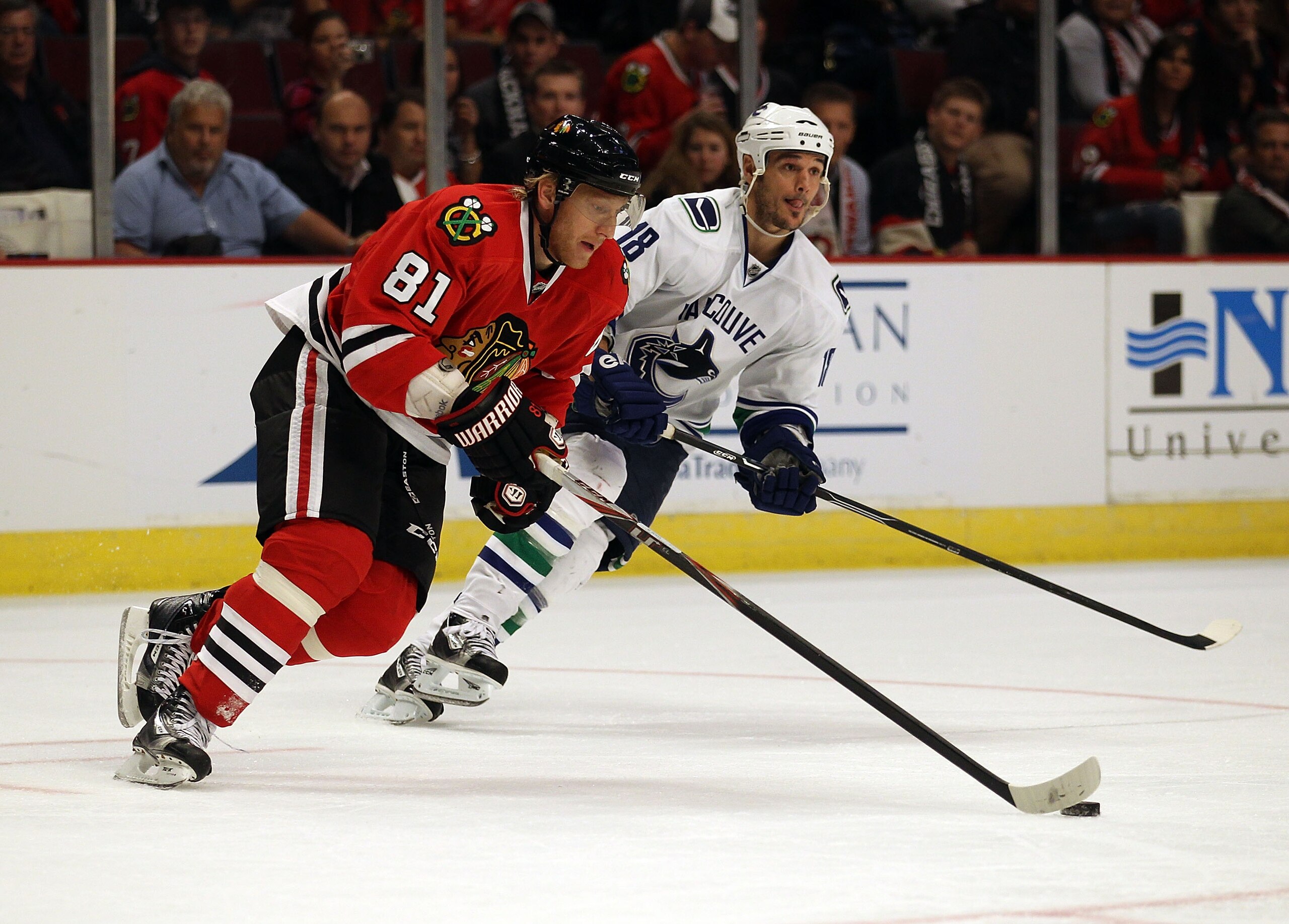 CHICAGO - OCTOBER 20: Marian Hossa #81 of the Chicago Blackhawks controls the puck under pressure from Peter Schaefer #18 of the Vancouver Canucks at the United Center on October 20, 2010 in Chicago, Illinois. The Blackhawks defeated the Canucks 2-1 in a