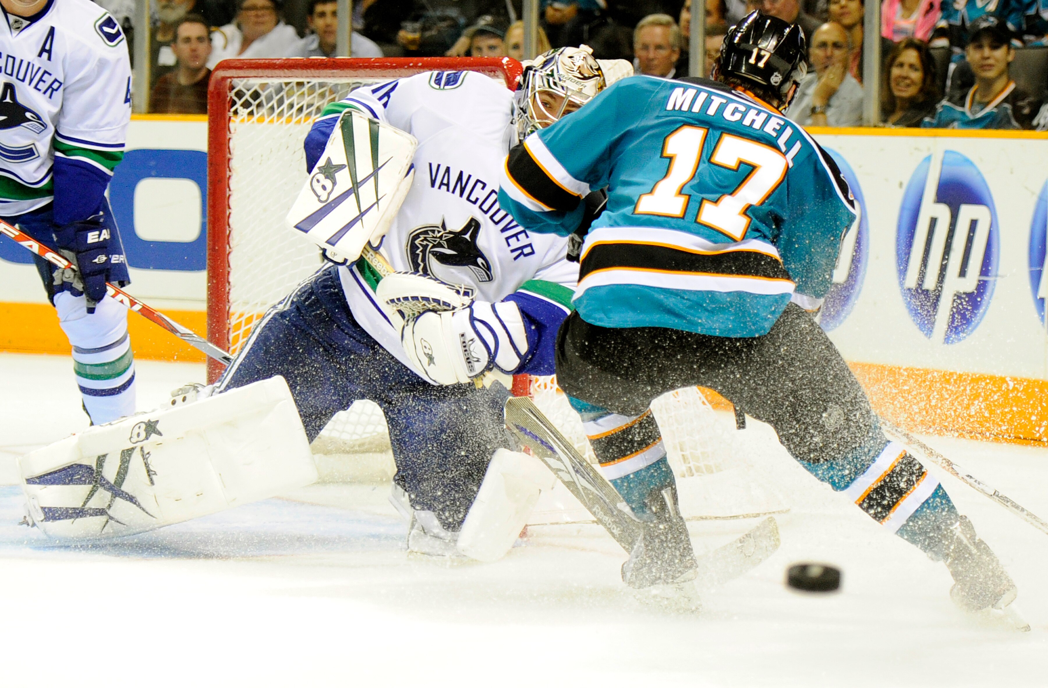 SAN JOSE, CA - SEPTEMBER 29: Goalie Eddie Lack #76 of the Vancouver Canucks clears the puck through the legs of Torrey Mitchell #17 of the San Jose Sharks during their preseason game against the San Jose Sharks at the HP Pavilion on September 29, 2010 in