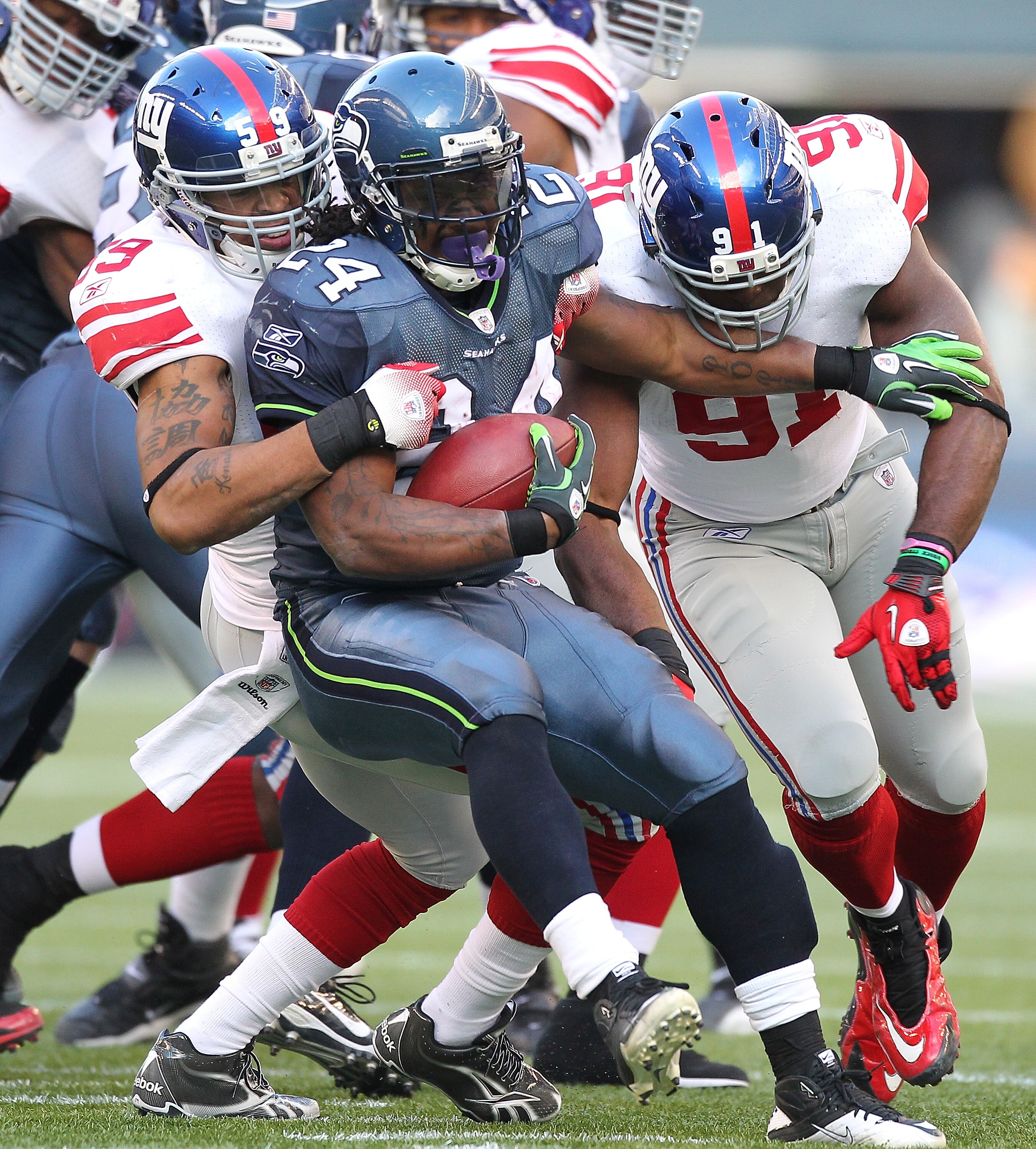 SEATTLE - NOVEMBER 07:  Running back Marshawn Lynch #24 of the Seattle Seahawks is tackled by Michael Boley #59 and defensive end Justin Tuck #91 of the New York Giants at Qwest Field on November 7, 2010 in Seattle, Washington. The Giants defeated the Sea