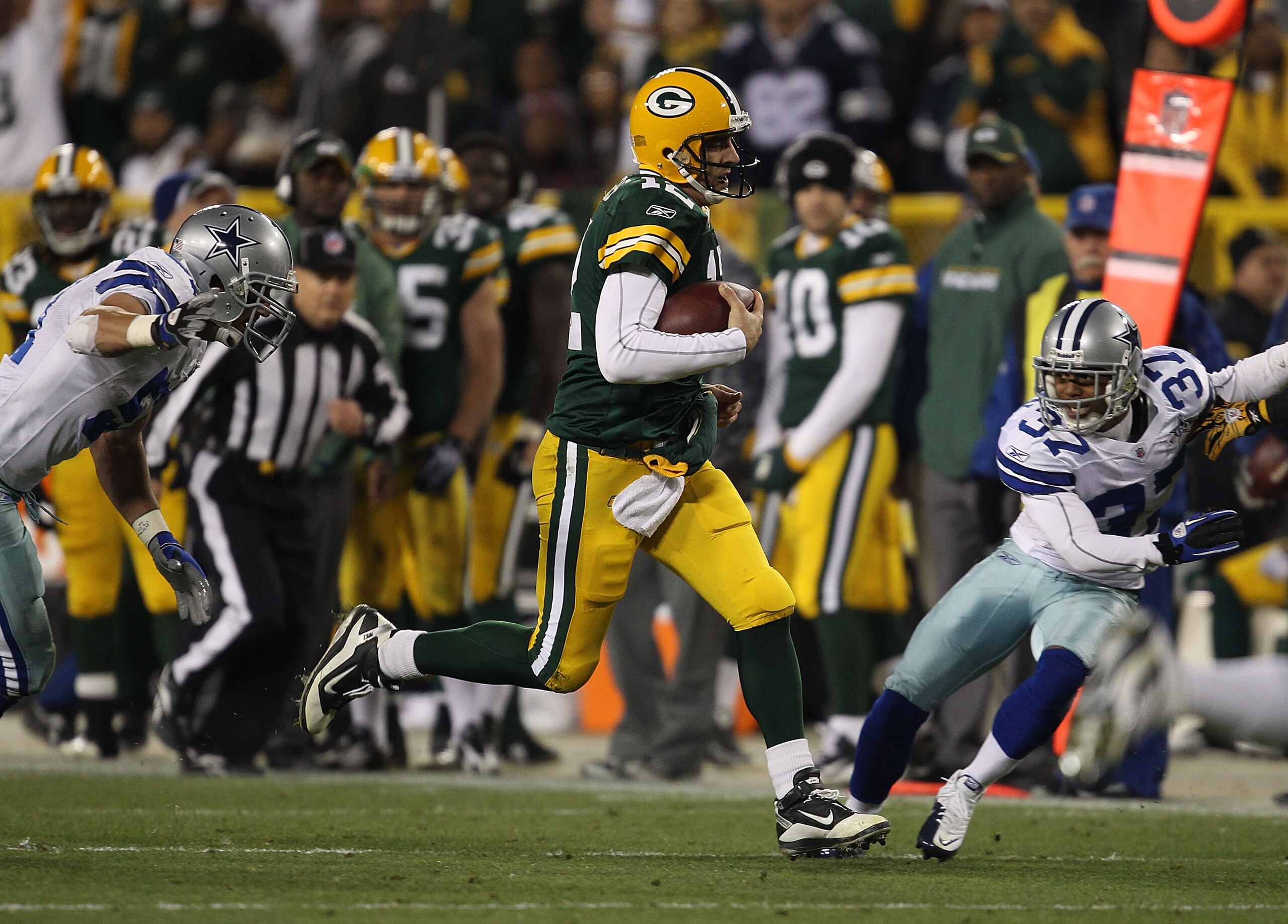 GREEN BAY, WI - NOVEMBER 07: Aaron Rodgers #12 of the Green Bay Packers runs for a first down between Keith Brooking #51 and Bryan McCann #37 of the Dallas Cowboys at Lambeau Field on November 7, 2010 in Green Bay, Wisconsin. (Photo by Jonathan Daniel/Get