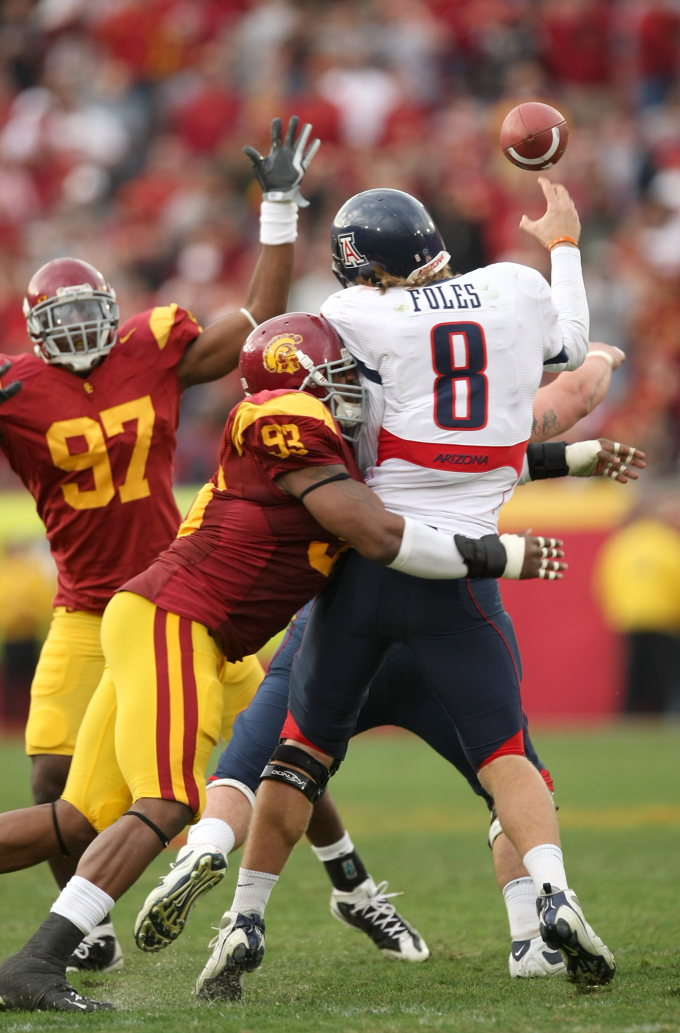 LOS ANGELES, CA - DECEMBER 05:  Quarterback Nick Foles #8 of the Arizona Wildcats is hit as he throws a pass by defensive end Everson Griffen #93 of the USC Trojans on December 5, 2009 at the Los Angeles Coliseum in Los Angeles, California. Arizona won 21