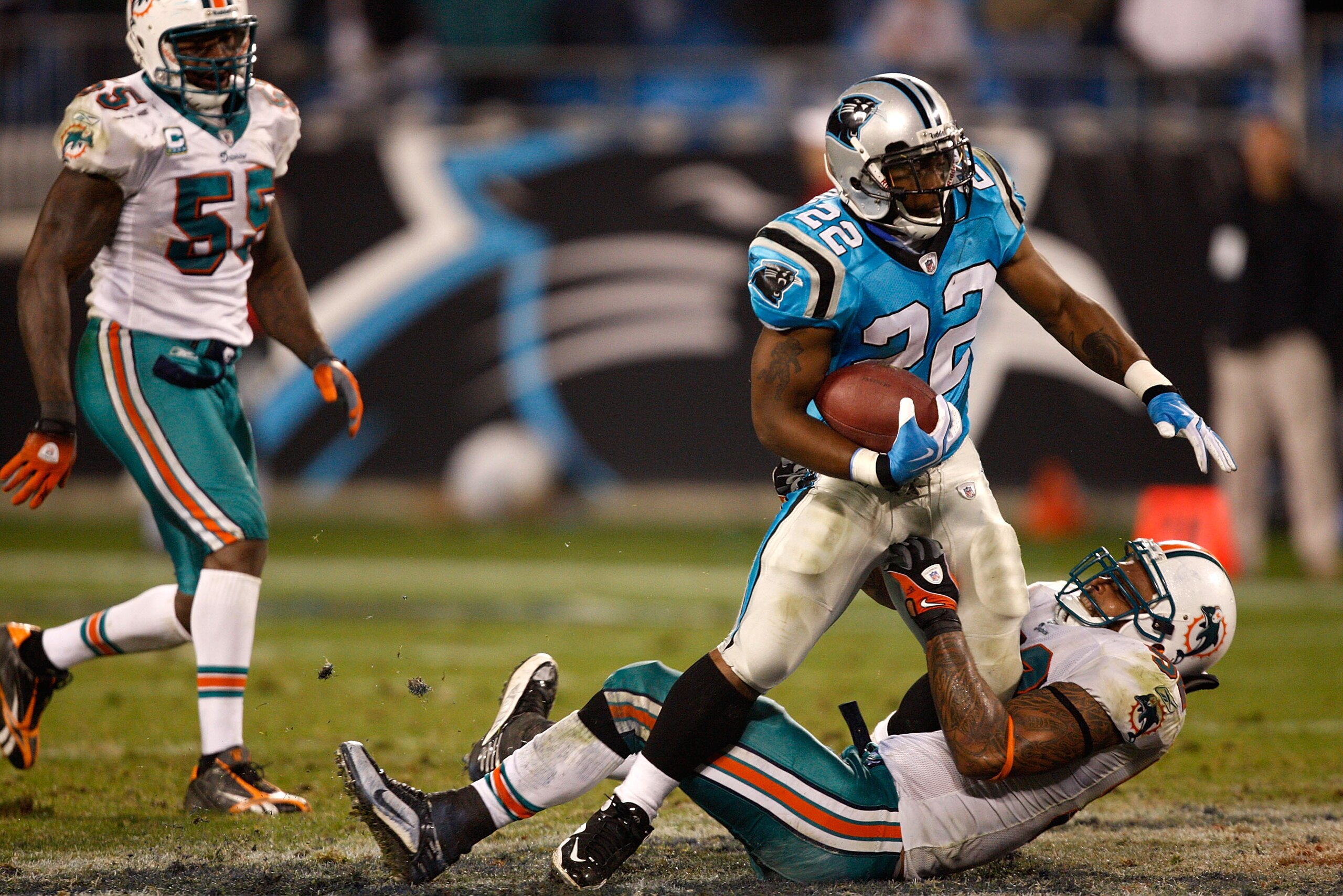 CHARLOTTE, NC - NOVEMBER 19:  Channing Crowder #52 of the Miami Dolphins tries to tackle Tyrell Sutton #22 of the Carolina Panthers during their game at Bank of America Stadium on November 19, 2009 in Charlotte, North Carolina.  (Photo by Streeter Lecka/G