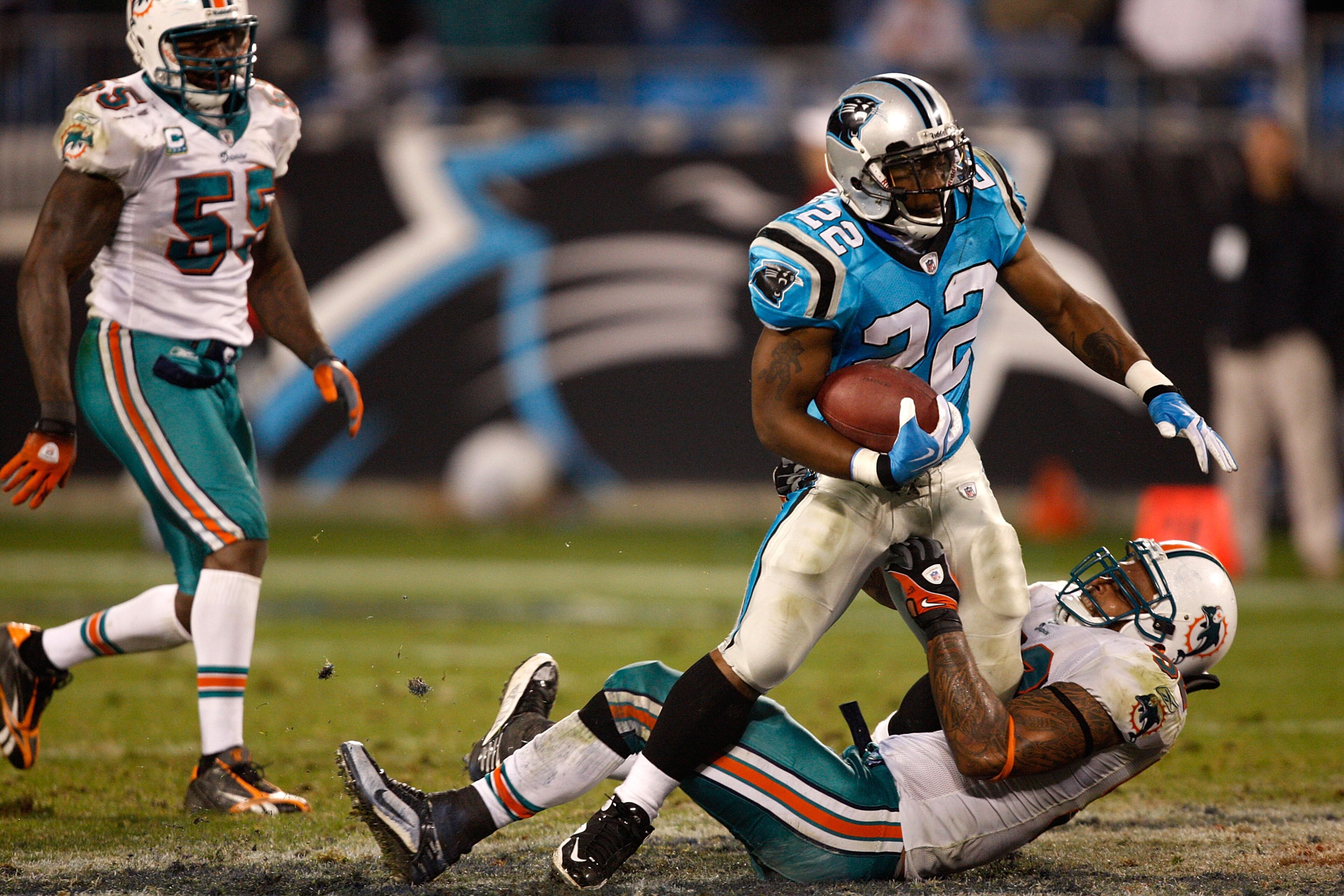 CHARLOTTE, NC - NOVEMBER 19:  Channing Crowder #52 of the Miami Dolphins tries to tackle Tyrell Sutton #22 of the Carolina Panthers during their game at Bank of America Stadium on November 19, 2009 in Charlotte, North Carolina.  (Photo by Streeter Lecka/G
