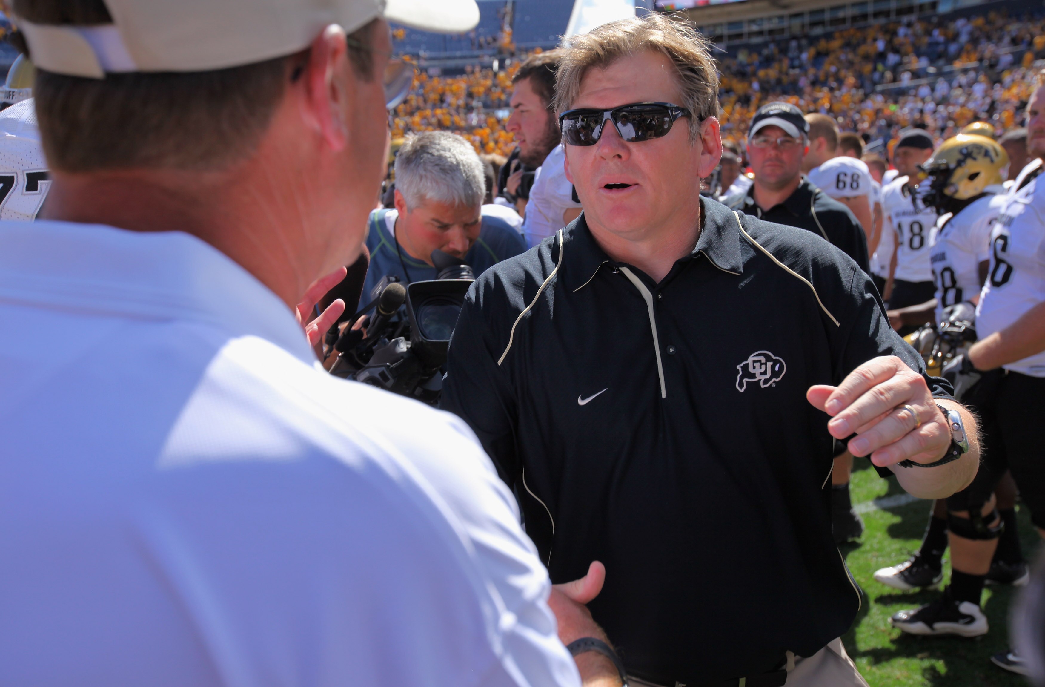 DENVER - SEPTEMBER 04:  Head coach Dan Hawkins (R) of the Colorado Buffaloes greats head coach Steve Fairchild (L) of the Colorado State Rams talk after the Rocky Mountain Showdown at INVESCO Field at Mile High on September 4, 2010 in Denver, Colorado. Co