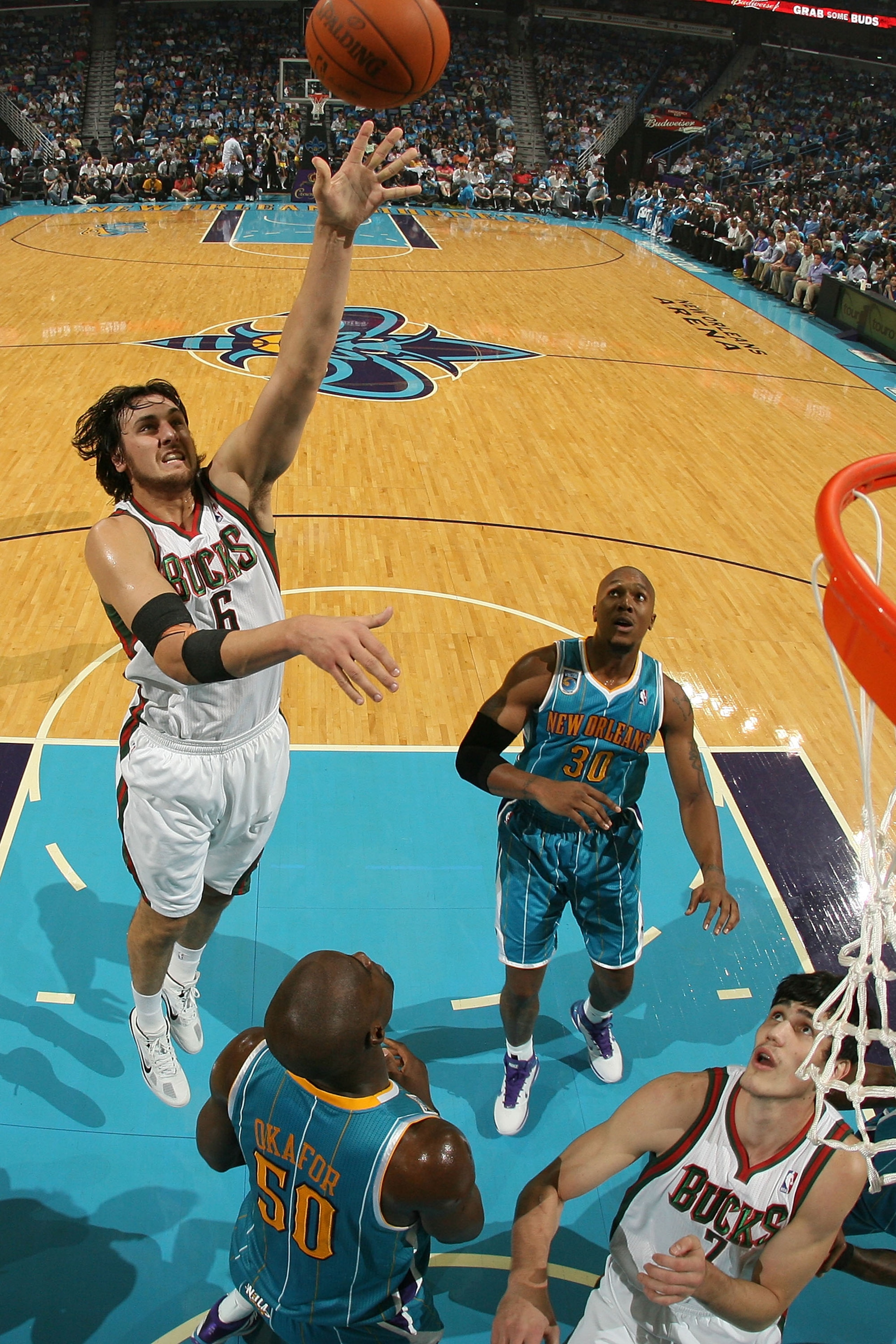 NEW ORLEANS - OCTOBER 27:  Andrew Bogut #6 of the Milwaukee Bucks shoots the ball over Emeka Okafor #50 of the New Orleans Hornets at the New Orleans Arena on October 27, 2010 in New Orleans, Louisiana.   The Hornets defeated the Bucks 95-91.   NOTE TO US