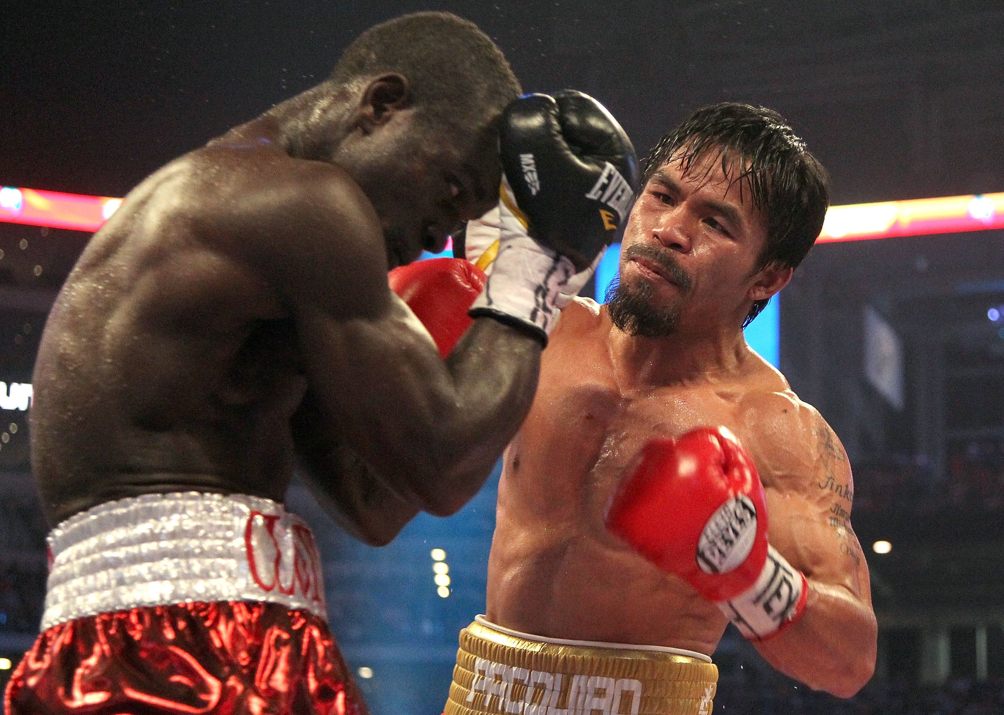 ARLINGTON, TX - MARCH 13:  (R-L) Manny Pacquiao of the Philippines throws a right to the head of Joshua Clottey of Ghana during the WBO welterweight title fight at Cowboys Stadium on March 13, 2010 in Arlington, Texas. Pacquiao defeated Clottey by unanimo