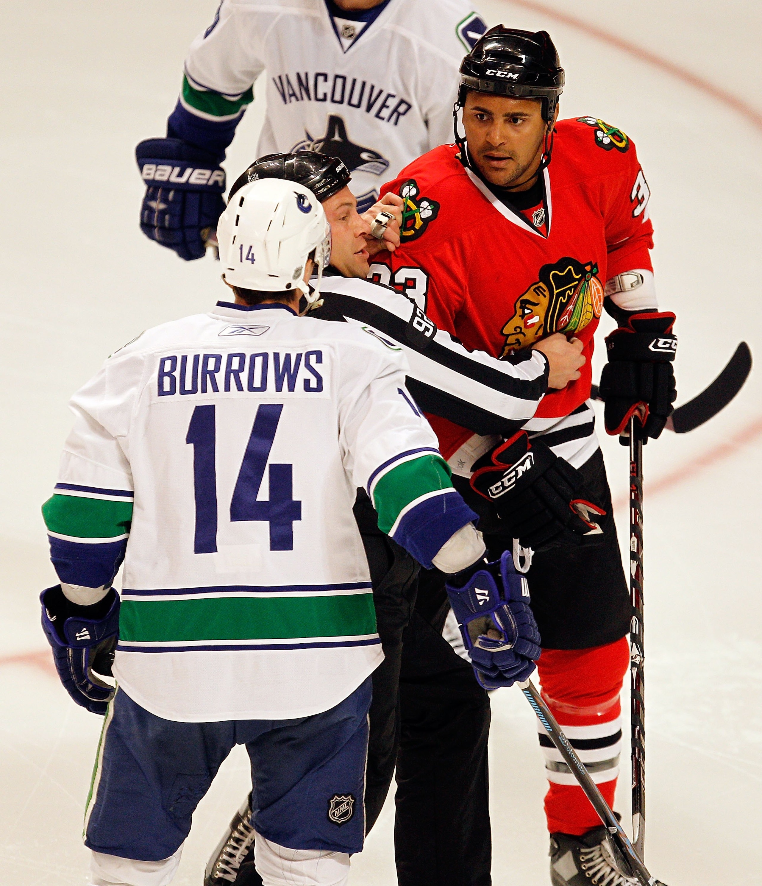 CHICAGO - MARCH 05: A referee tries to keep Dustin Byfuglien #33 of the Chicago Blackhawks away from Alexander Burrows #14 of the Vancouver Canucks at the United Center on March 5, 2010 in Chicago, Illinois. The Blackhawks defeated the Canucks 6-3. (Photo