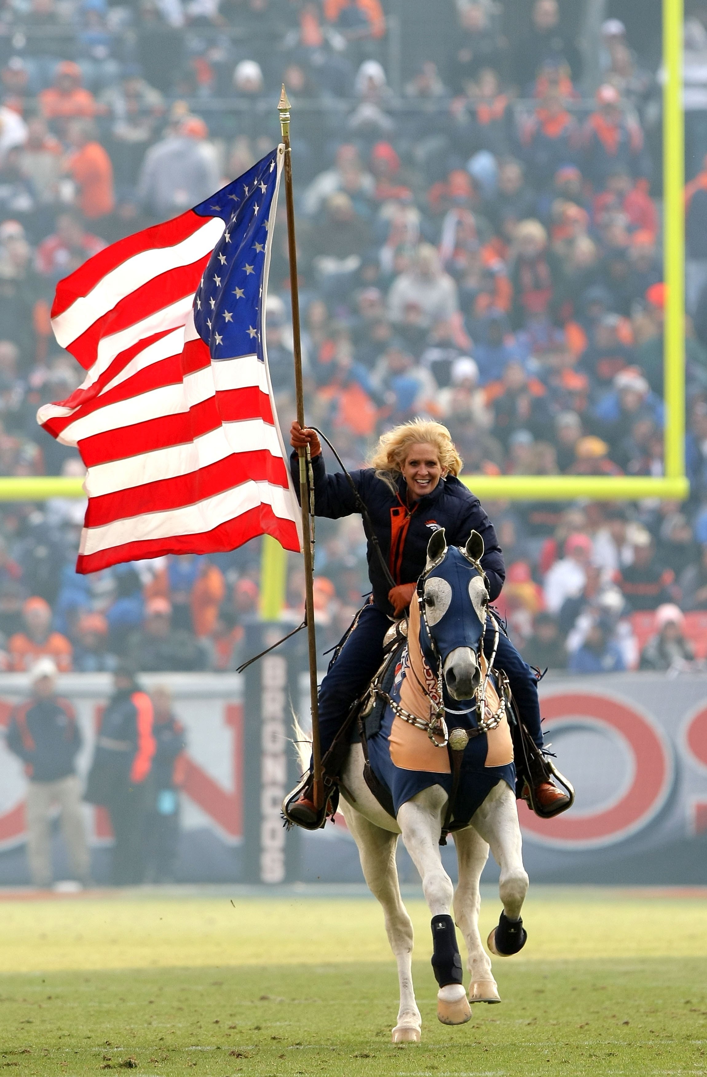 DENVER - JANUARY 03:  Ann Judge-Wegener carries the Stars and Stripes as she rides Thunder across the playing field after the Denver Broncos scored against the Kansas City Chiefs during NFL action at Invesco Field at Mile High on January 3, 2010 in Denver