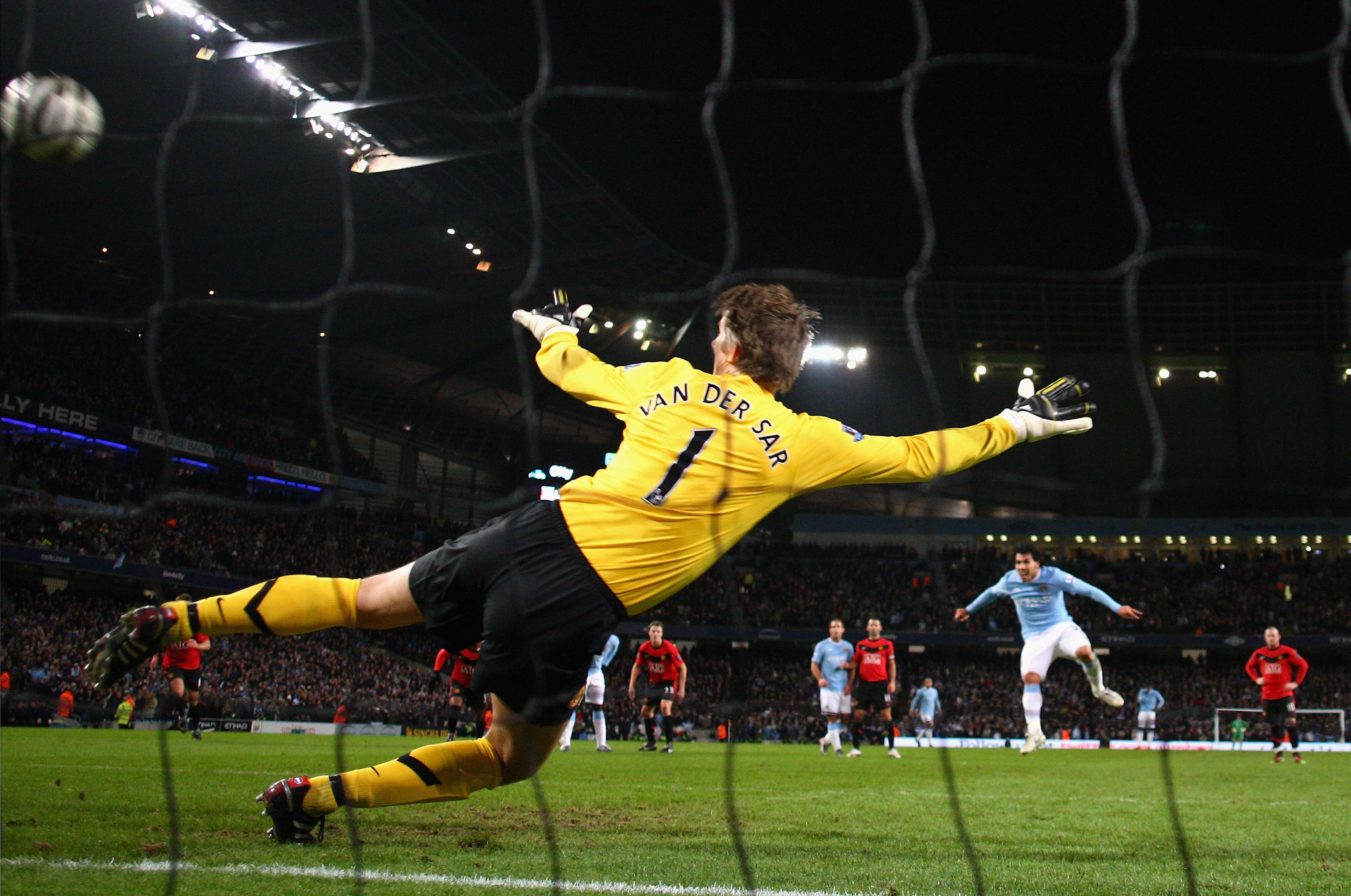 MANCHESTER, ENGLAND - JANUARY 19:  Carlos Tevez of Manchester City scores his team's first goal past Edwin Van der Sar of Manchester United during the Carling Cup Semi Final match between Manchester City and Manchester United at the City of Manchester Sta