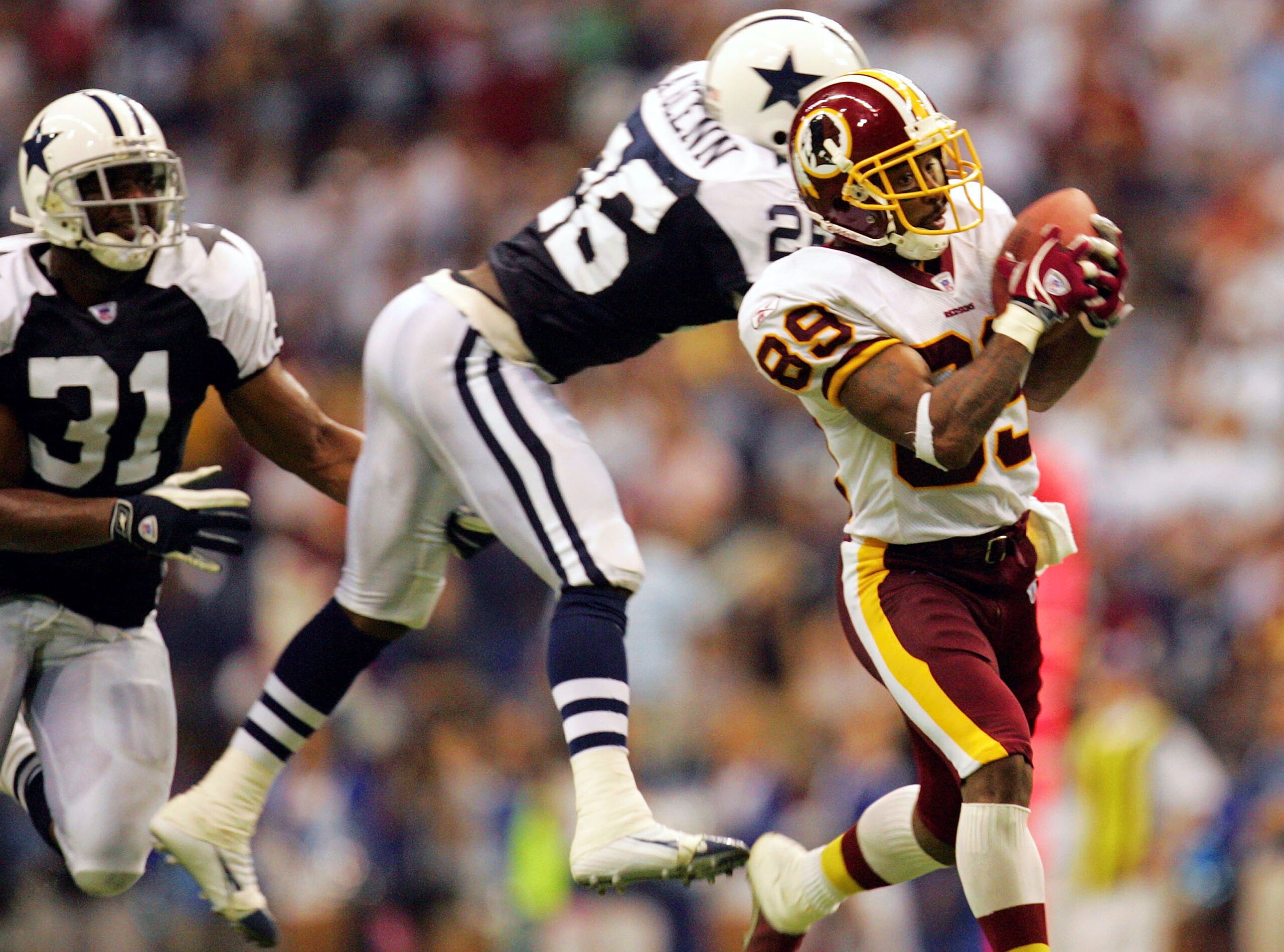 IRVING, TX - SEPTEMBER 19:  Wide receiver Santana Moss #89 of the Washington Redskins makes a pass reception and runs for a touchdown past Aaron Glenn #26 of the Dallas Cowboys on September 19, 2005 at Texas Stadium in Irving, Texas. The Redskins defeated