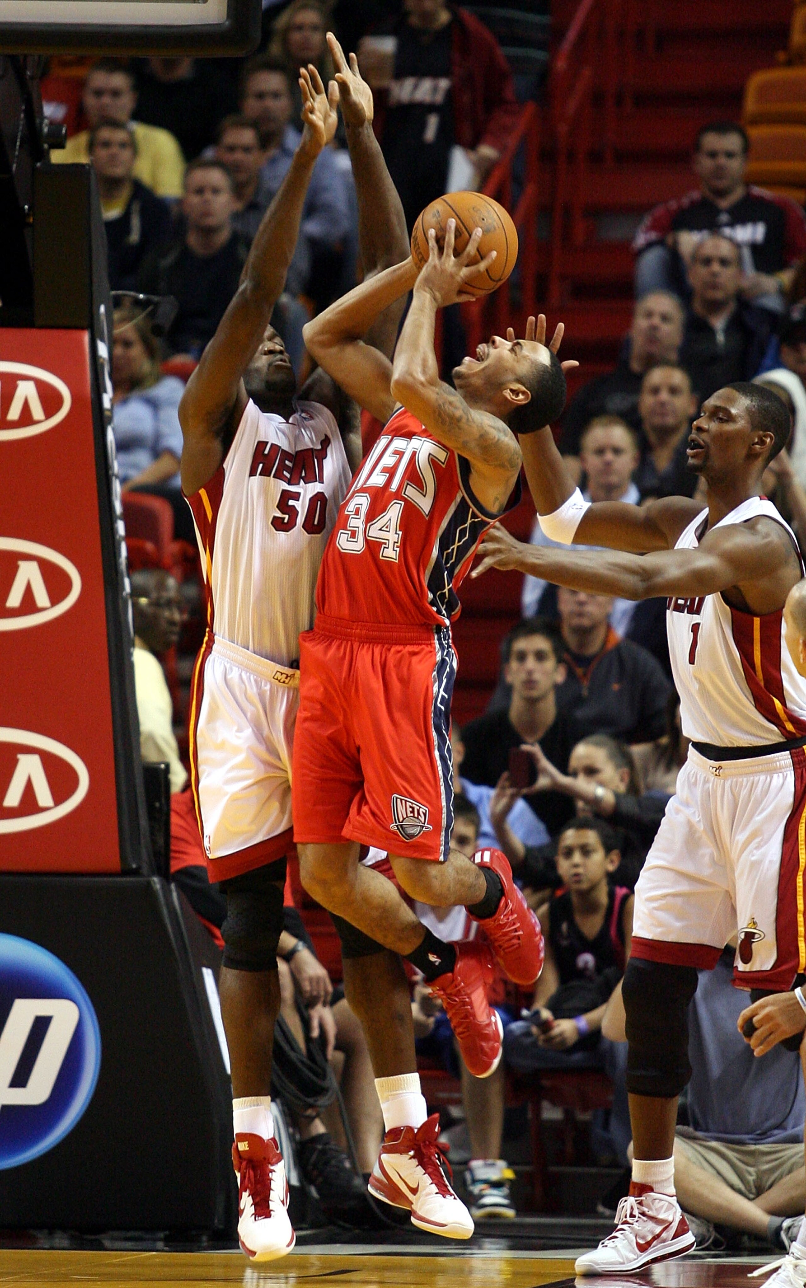 MIAMI - NOVEMBER 06:  Guard Devin Harris #34 of the New Jersey Nets shoots against Joel Anthony #50 and Chris Bosh #1 of the Miami Heat at American Airlines Arena on November 6, 2010 in Miami, Florida. NOTE TO USER: User expressly acknowledges and agrees