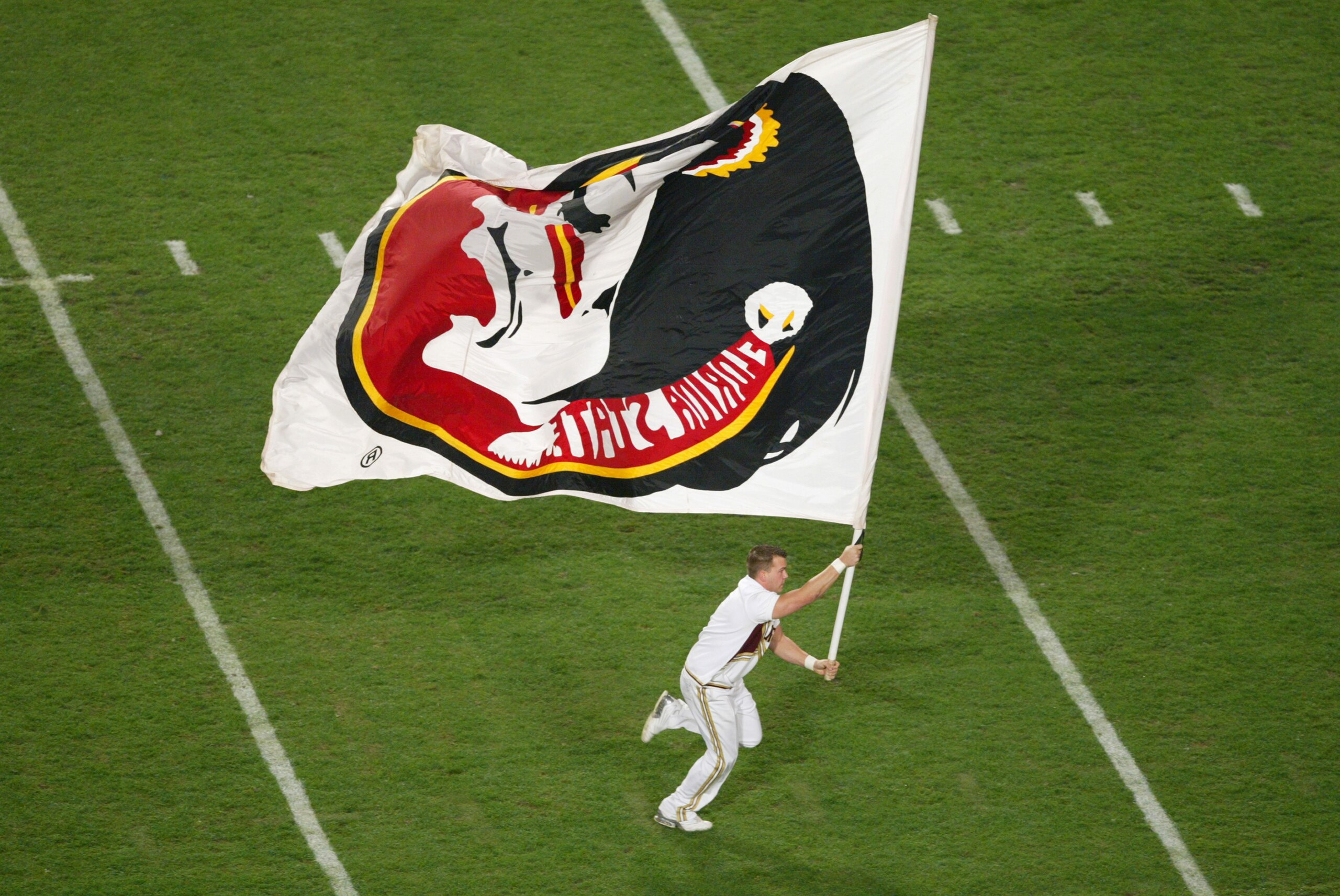 MIAMI - JANUARY 1:  A Florida State Seminoles cheerleader runs across the field carring a Seminoles flag during the 2004 Orange Bowl game against the Miami Hurricanes on January 1, 2004 at Pro Player Stadium in Miami, Florida. Miami defeated Forida State