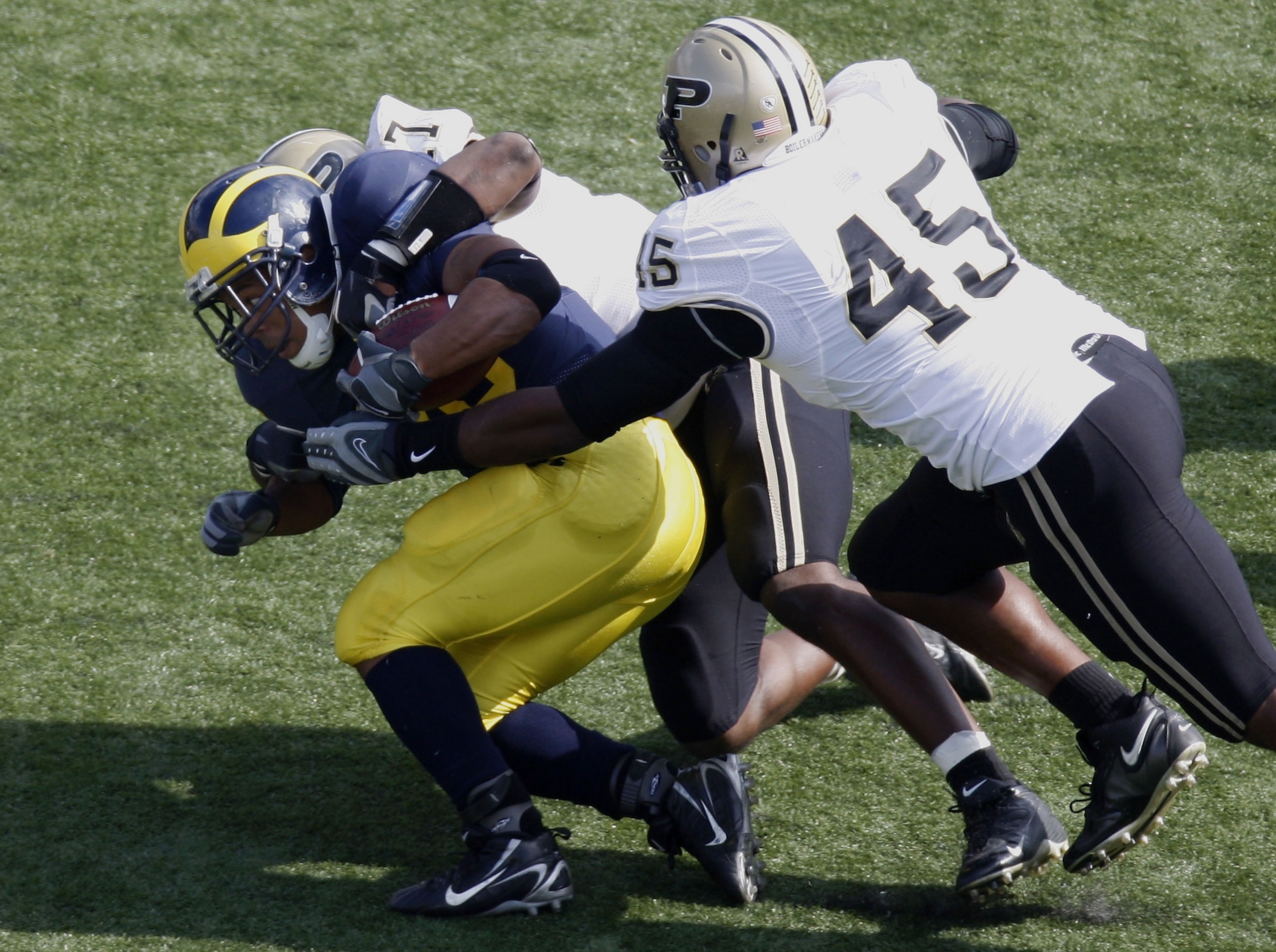 ANN ARBOR, MI - OCTOBER 13:  Mike Hart #20 of the Michigan Wolverines is gets injured while being tackled by Eugene Bright #45 and Josh Ferguson #17 of the Purdue Boilermakers on October 13, 2007 at Michigan Stadium in Ann Arbor, Michigan. Michigan won th