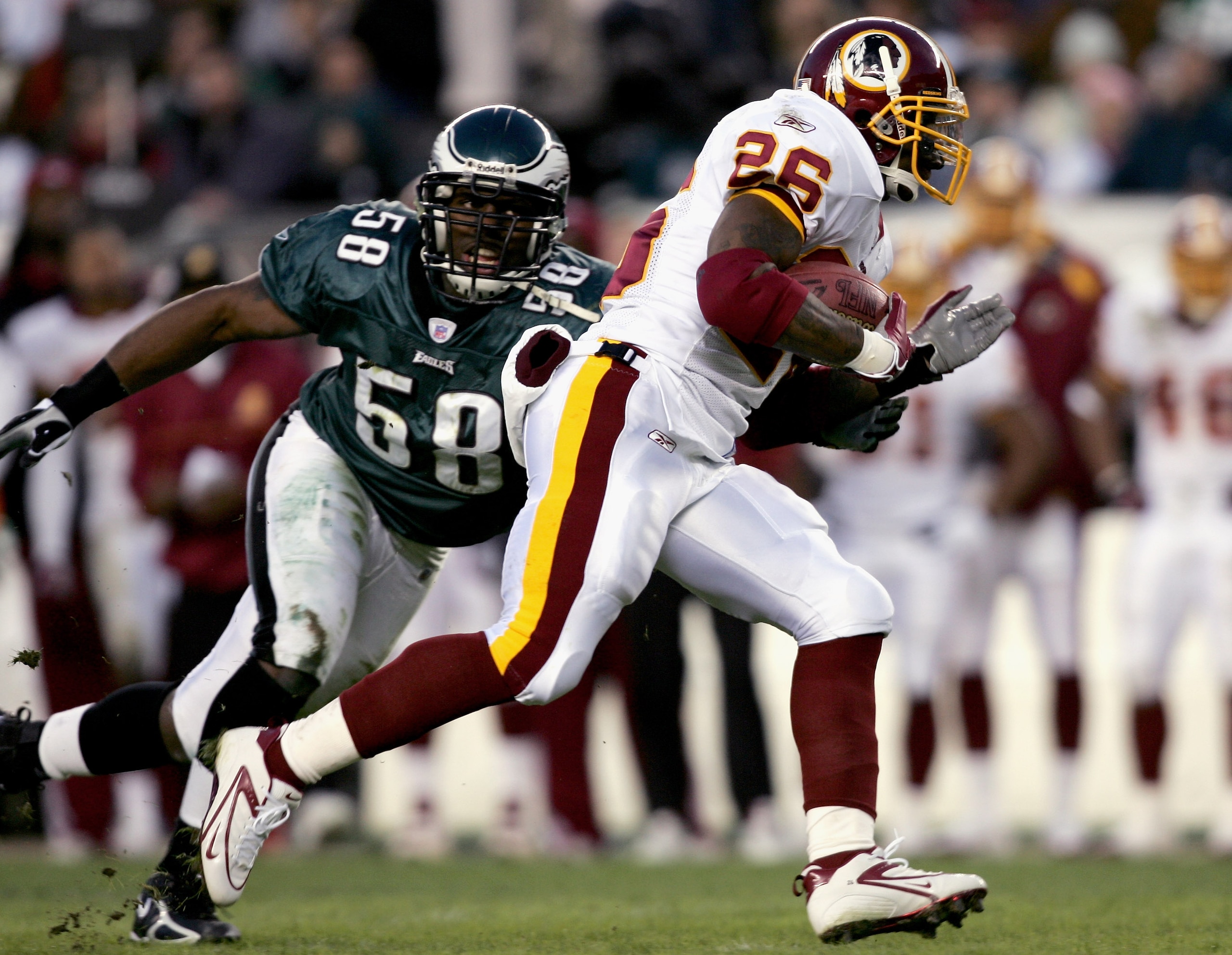 PHILADELPHIA - JANUARY 01:  Runningback Clinton Portis #26 of the Washington Redskins carries the ball away from Trent Cole #58 of the Philadelphia Eagles during the first quarter of the game on January 1, 2006 at Lincoln Financial Field in Philadelphia,