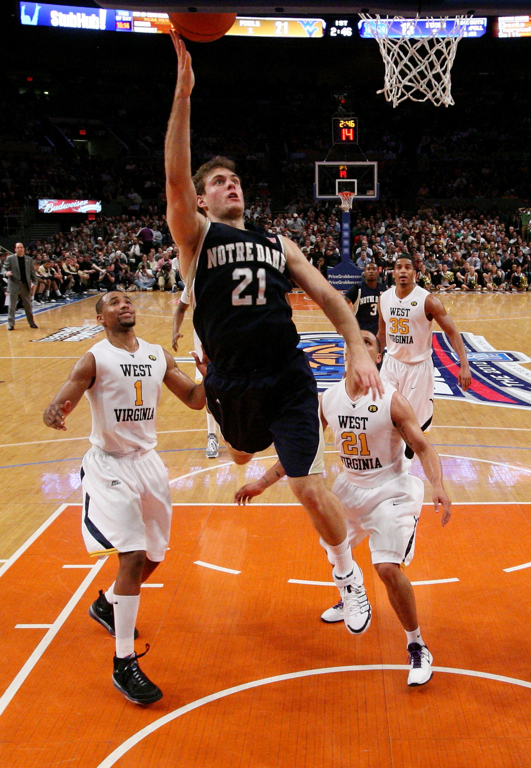 NEW YORK - MARCH 12: Tim Abromaitis #21 of the Notre Dame Fighting Irish drives to the hoop against Da'Sean Butler #1 and Joe Mazzulla #21 of the West Virginia Mountaineers during the semifinal of the 2010 Big East Tournament at Madison Square Garden on M