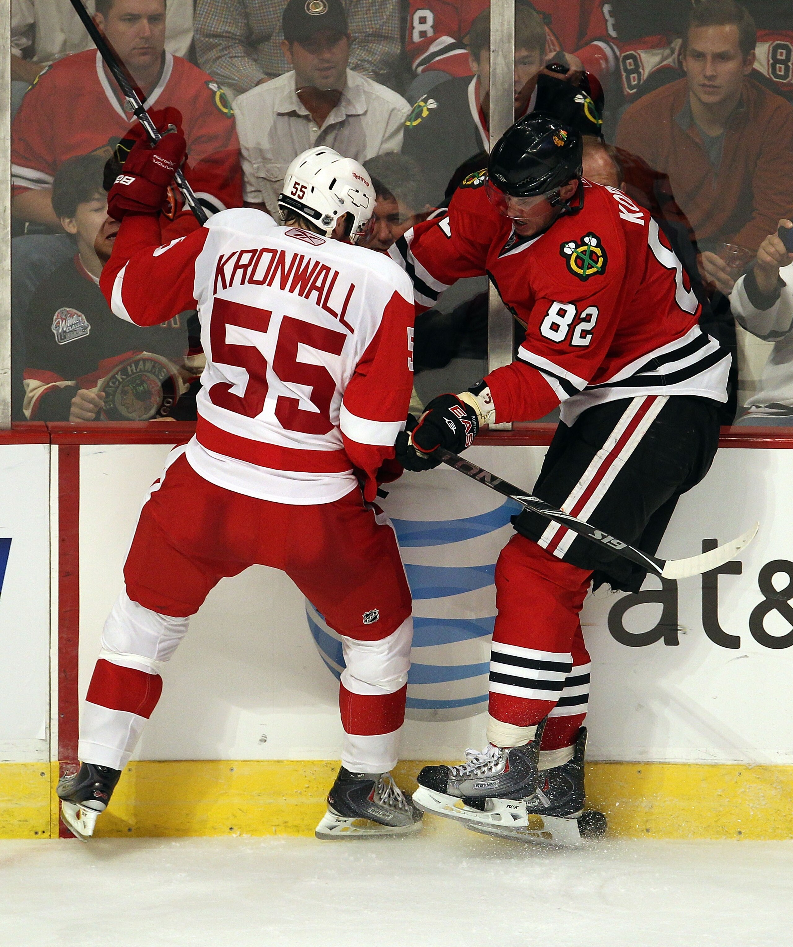 CHICAGO - OCTOBER 09: Tomas Kopecky #82 of the Chicago Blackhawks battles for the puck along the boards with Niklas Kronwall #55 of the Detroit Red Wings during the Blackhawks season home opening game at the United Center on October 9, 2010 in Chicago, Il