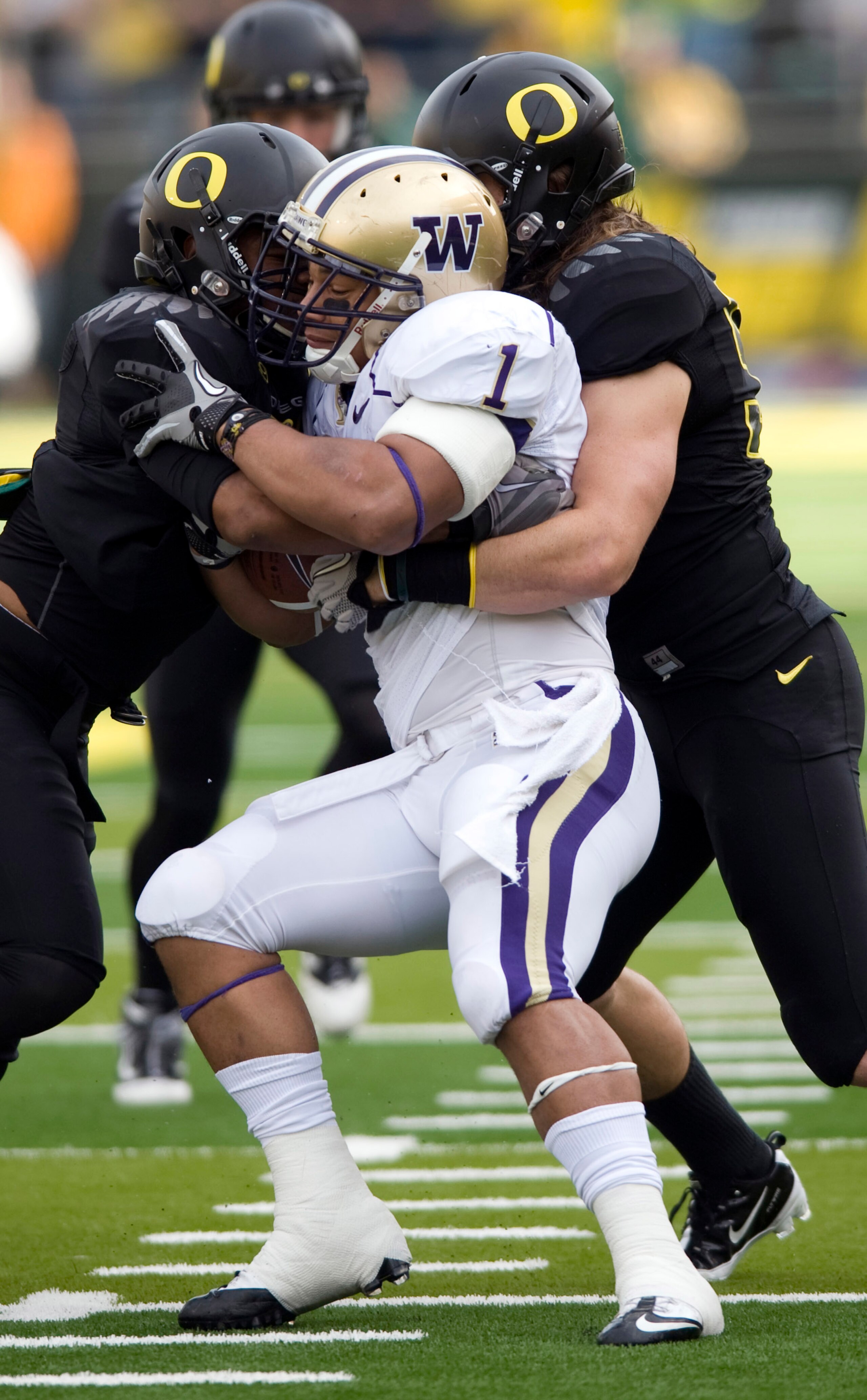 EUGENE, OR - NOVEMBER 6: Linebackers Spencer Paysinger #35 and Casey Matthews #55 of the Oregon Ducks gang up to tackle running back Chris Polk #1 of the Washington Huskies in the first quarter of the game at Autzen Stadium on November 6, 2010 in Eugene, 