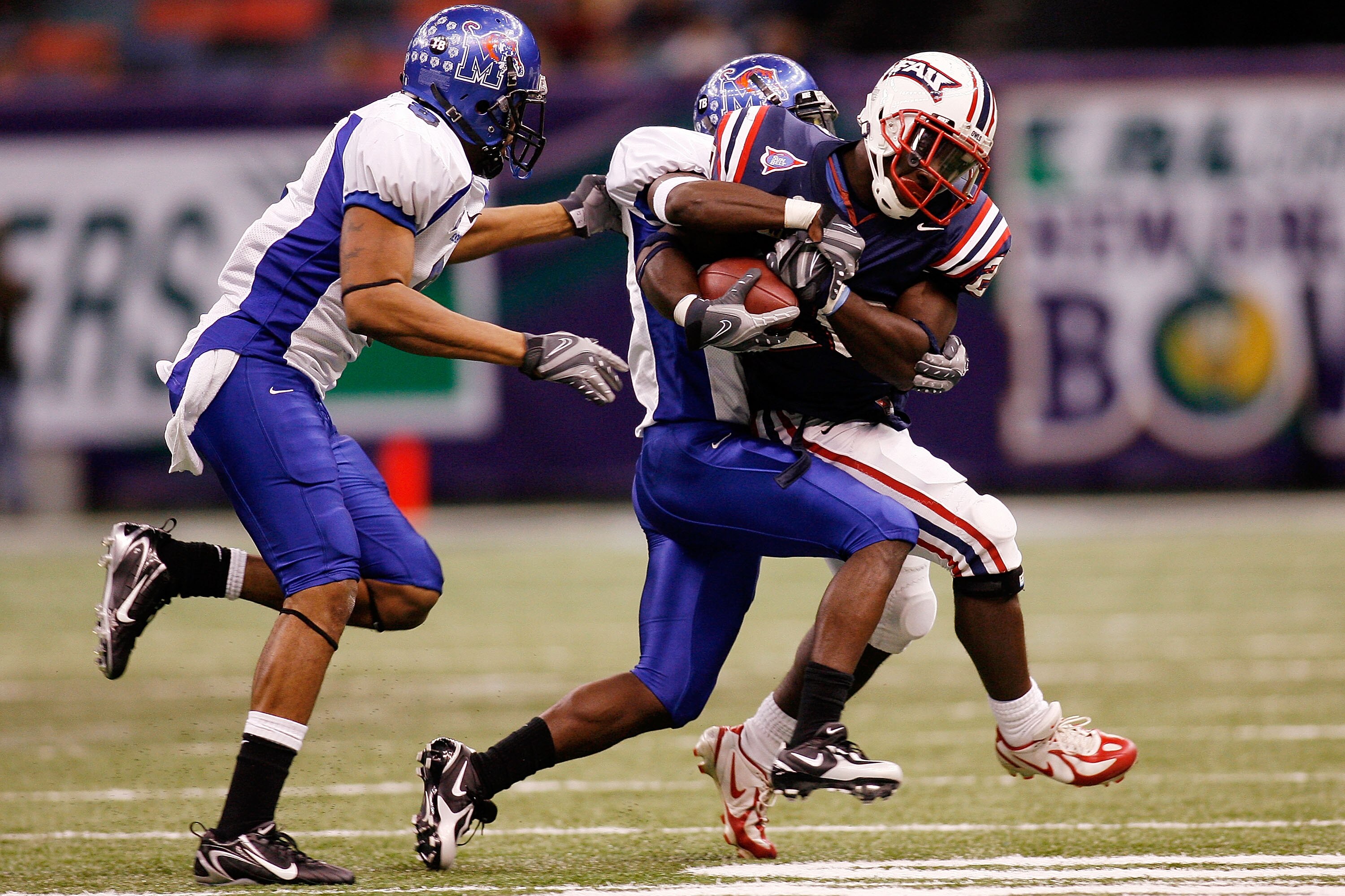 NEW ORLEANS - DECEMBER 21:  Charles Pierre #20 of the Florida Atlantic University Owls is tackled by LaKeitharun Ford #18 and Tony Bell #8 of the Memphis University Tigers  in the New Orleans Bowl on December 21, 2007 at the Louisiana Superdome in New Orl