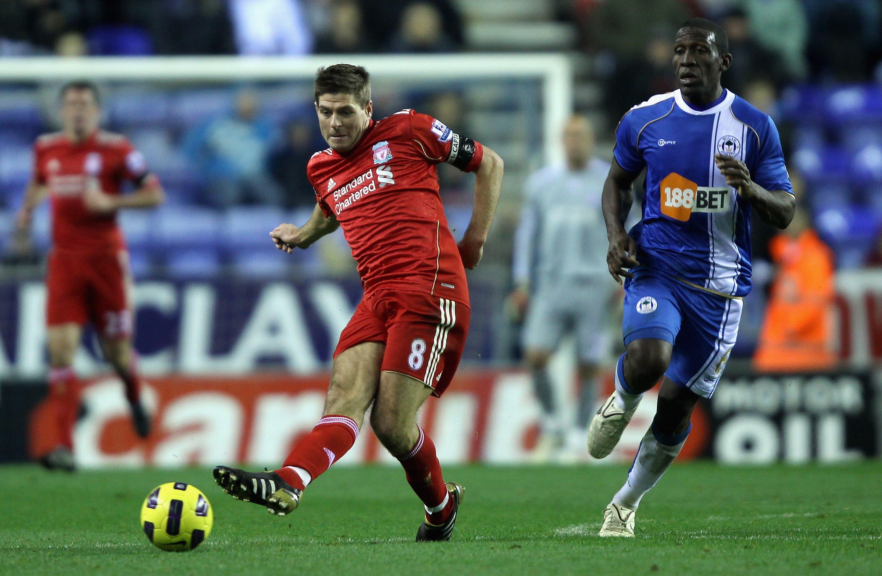 WIGAN, ENGLAND - NOVEMBER 10:  Steven Gerrard of Liverpool passes the ball away from Hendry Thomas of Wigan Athletic during the Barclays Premier League match between Wigan Athletic and Liverpool at DW Stadium on November 10, 2010 in Wigan, England.  (Phot
