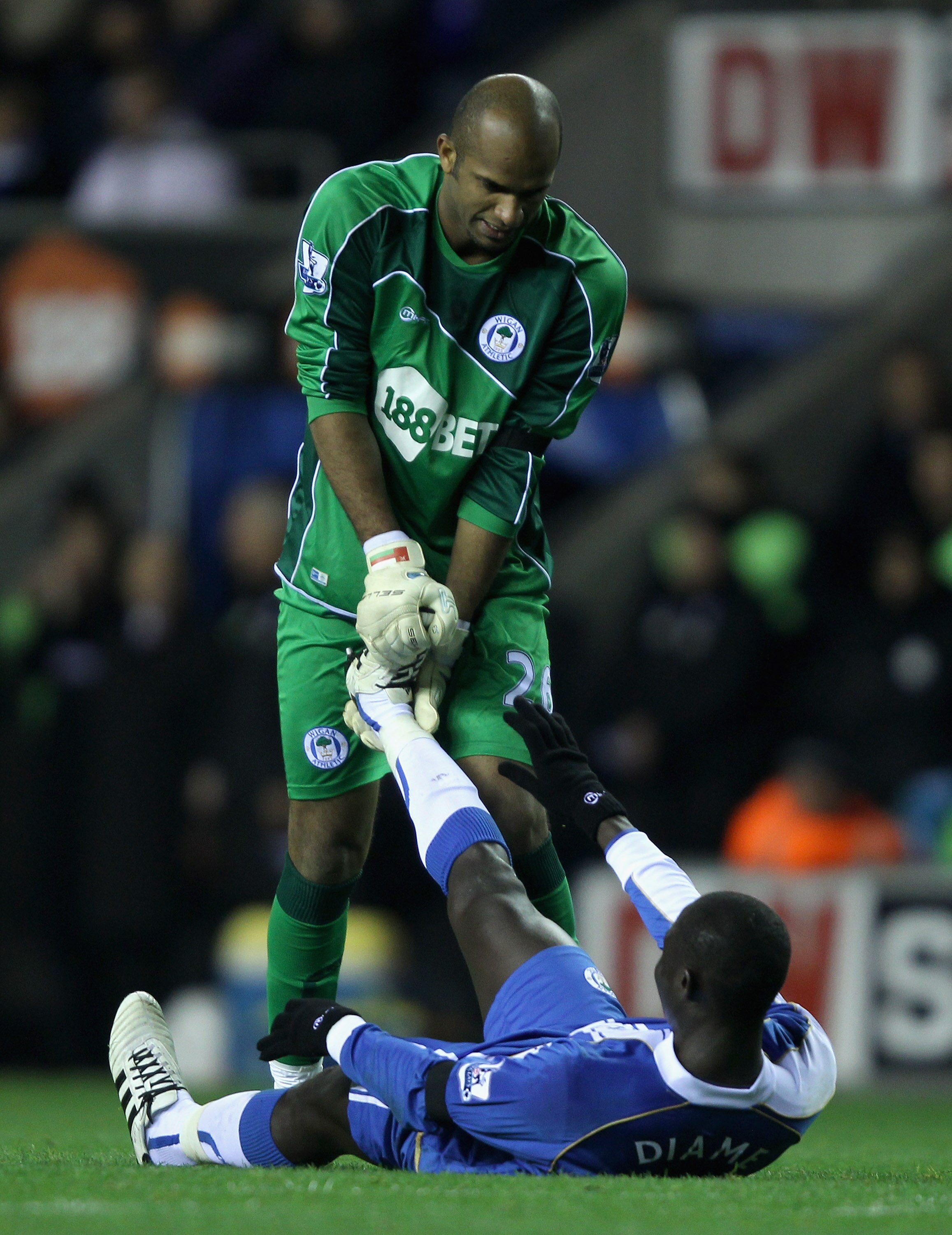WIGAN, ENGLAND - NOVEMBER 10:  Ali Al Habsi of Wigan Athletic helps team mate Mohammed Diame who is suffering from cramp during the Barclays Premier League match between Wigan Athletic and Liverpool at DW Stadium on November 10, 2010 in Wigan, England.  (