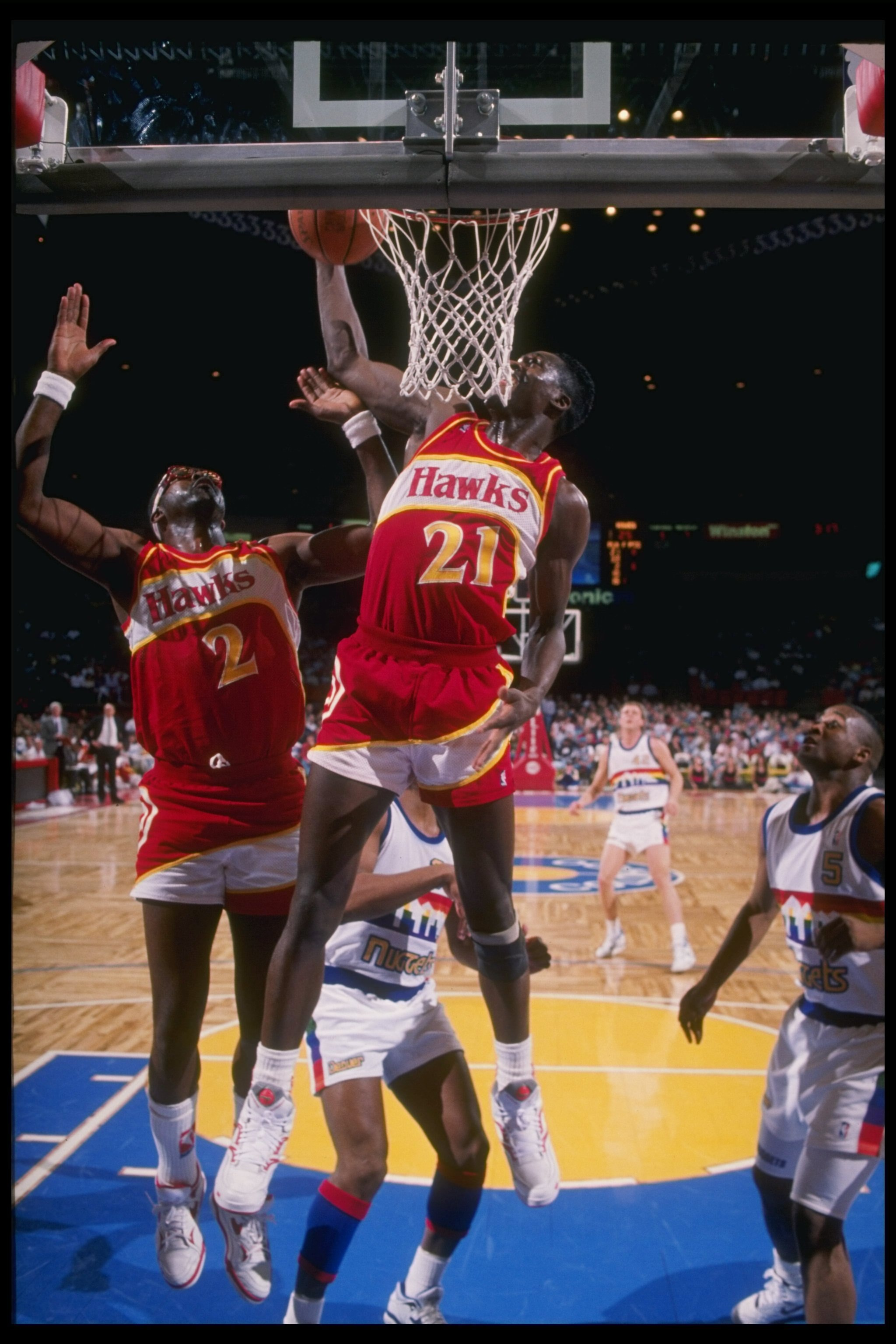 Forward Dominique Wilkins and center Moses Malone of the Atlanta Hawks jump for the ball during a game against the Denver Nuggets at the McNichols Sports Arena in Denver, Colorado.