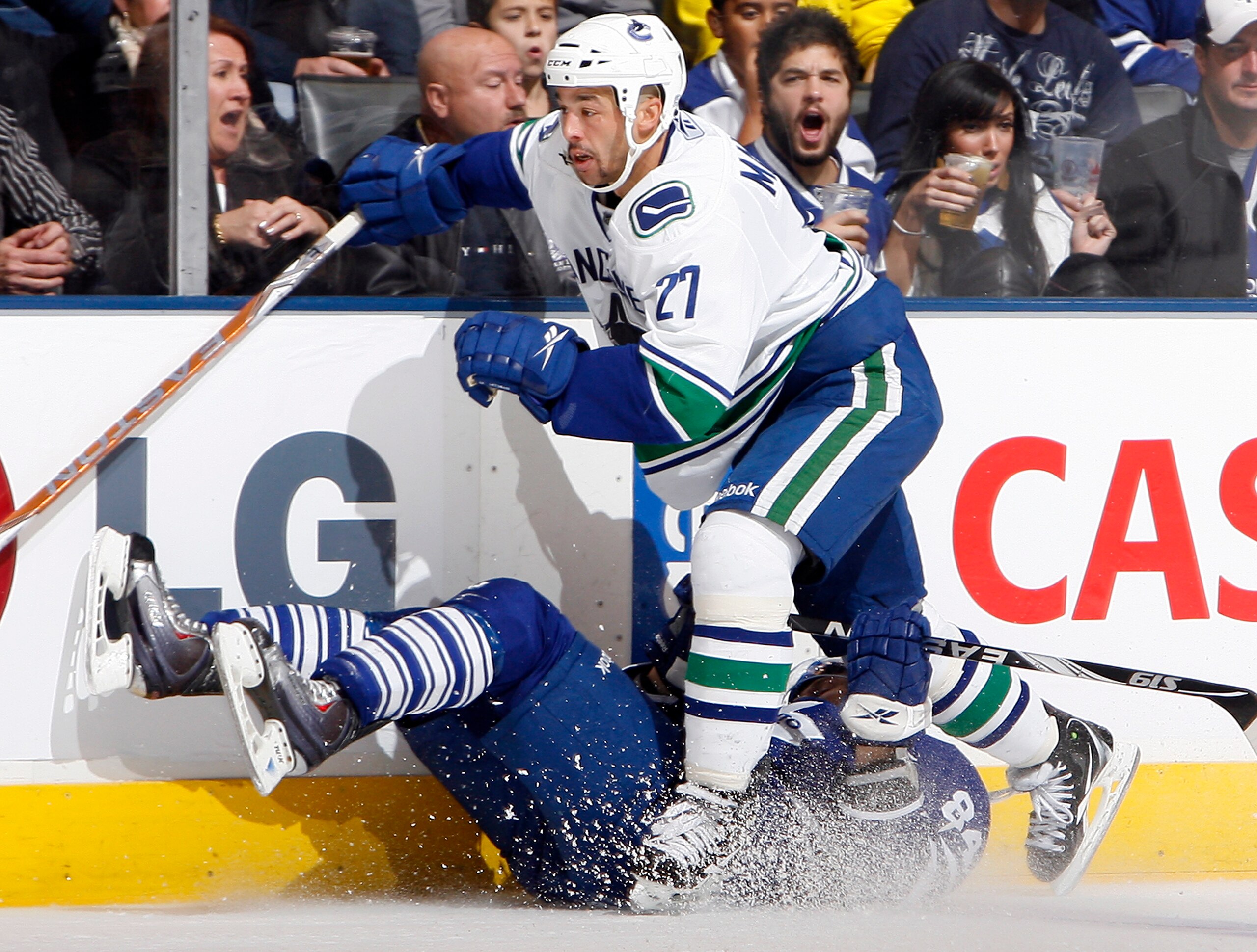 TORONTO - NOVEMBER 13: Mikhail Grabovski #84 of the Toronto Maple Leafs gets run over by Manny Malhotra #27 of the Vancouver Canucks during game action at the Air Canada Centre November 13, 2010 in Toronto, Ontario, Canada. (Photo by Abelimages / Getty Im