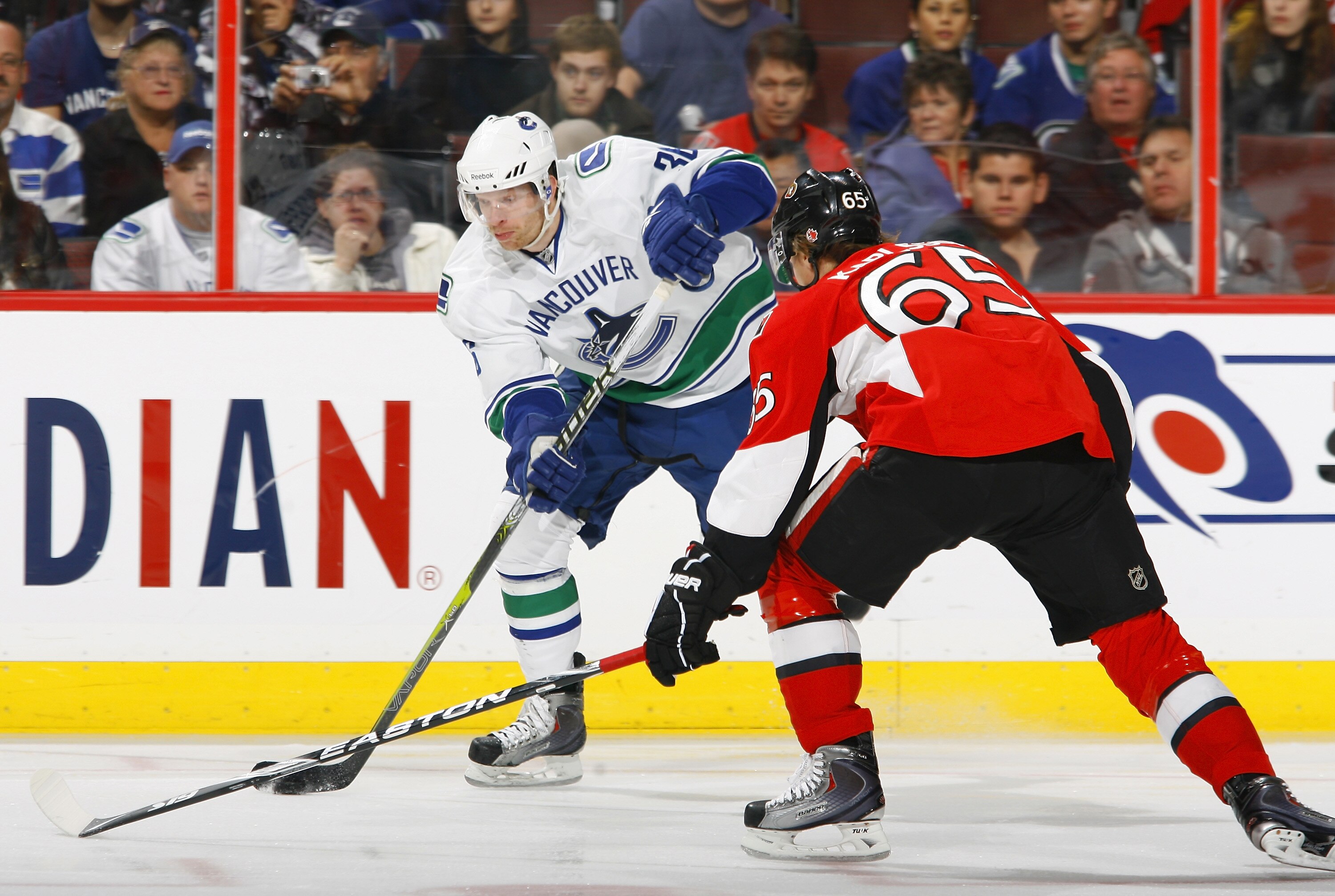 OTTAWA - NOVEMBER 11:  Jannik Hansen #36 of the Vancouver Canucks fires a wrist shot from the far boards while being closely checked by Erik Karlsson #65 of the Ottawa Senators in a game at Scotiabank Place on November 11, 2010 in Ottawa, Ontario, Canada.