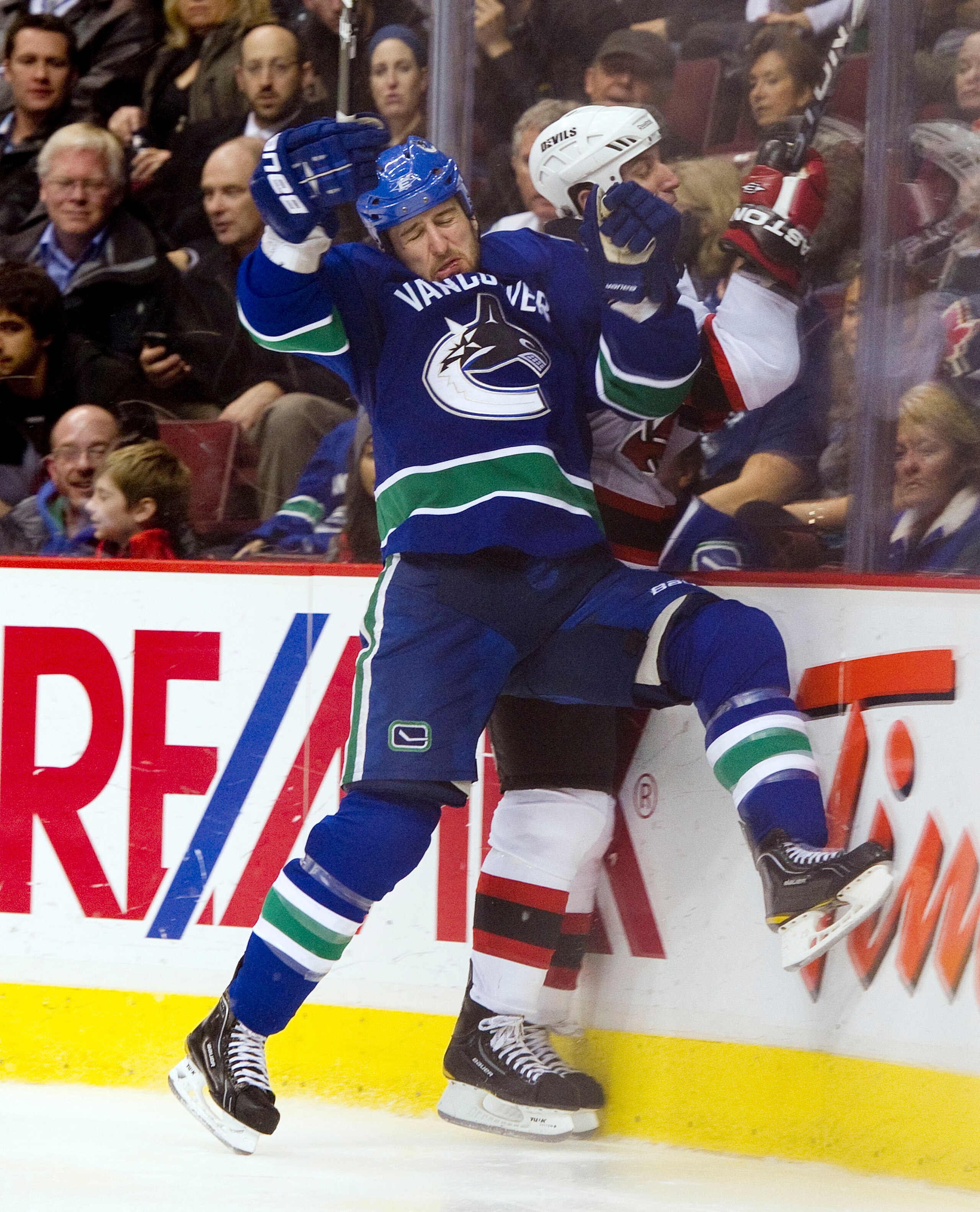 VANCOUVER, CANADA - NOVEMBER 01: Tanner Glass #15 of the Vancouver Canucks reacts after hitting Adam Mair #11 of the New Jersey Devils into the boards during the third period in NHL action on November 01, 2010 at Rogers Arena in Vancouver, British Columbi