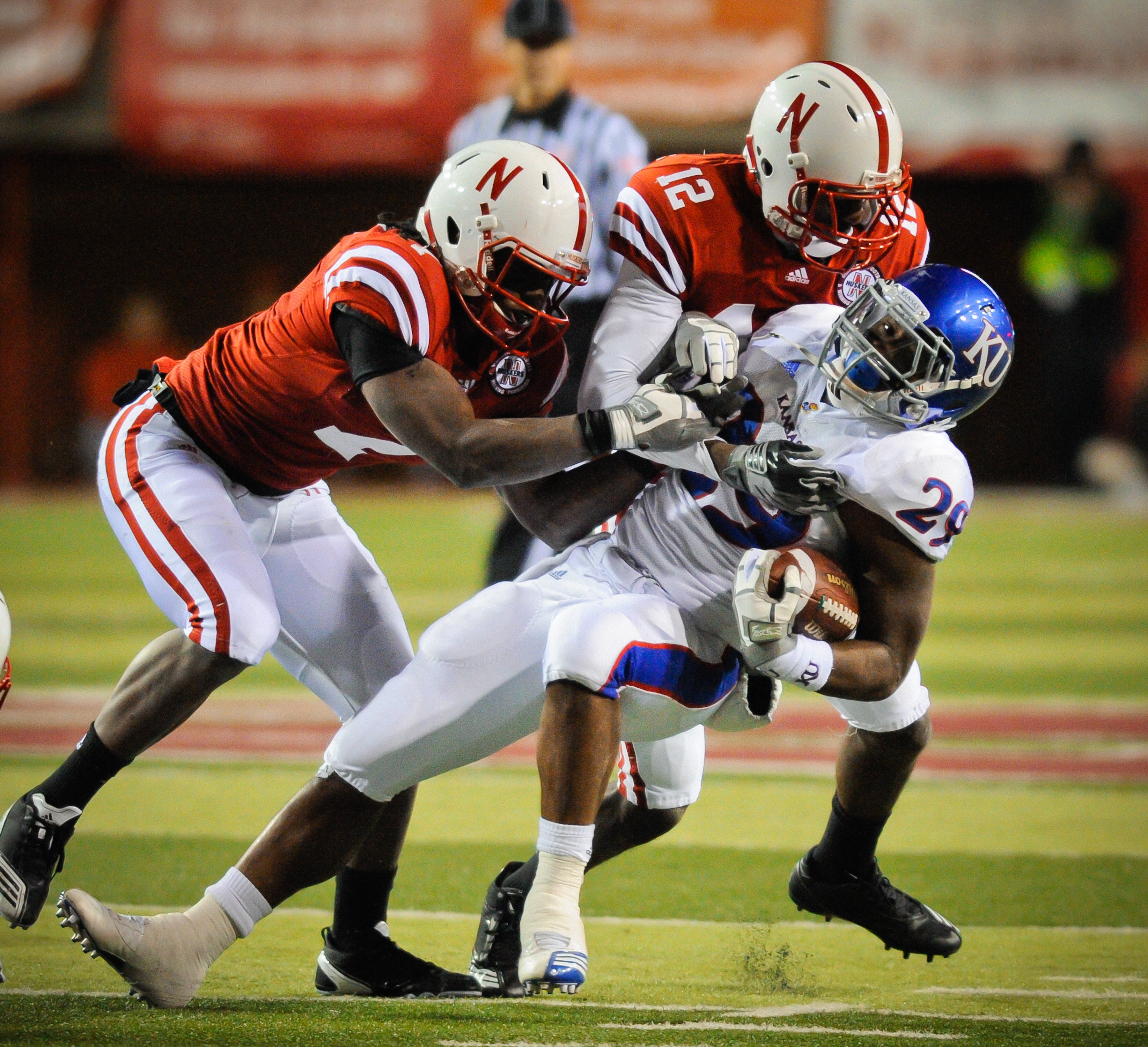 LINCOLN, NE - NOVEMBER 13: James Sims #29 of the Kansas Jayhawks is brought to the ground by Courtney Osborne #12 and DeJon Gomes #7 of the Nebraska Cornhuskers during second half action of their game at Memorial Stadium on November 13, 2010 in Lincoln, N