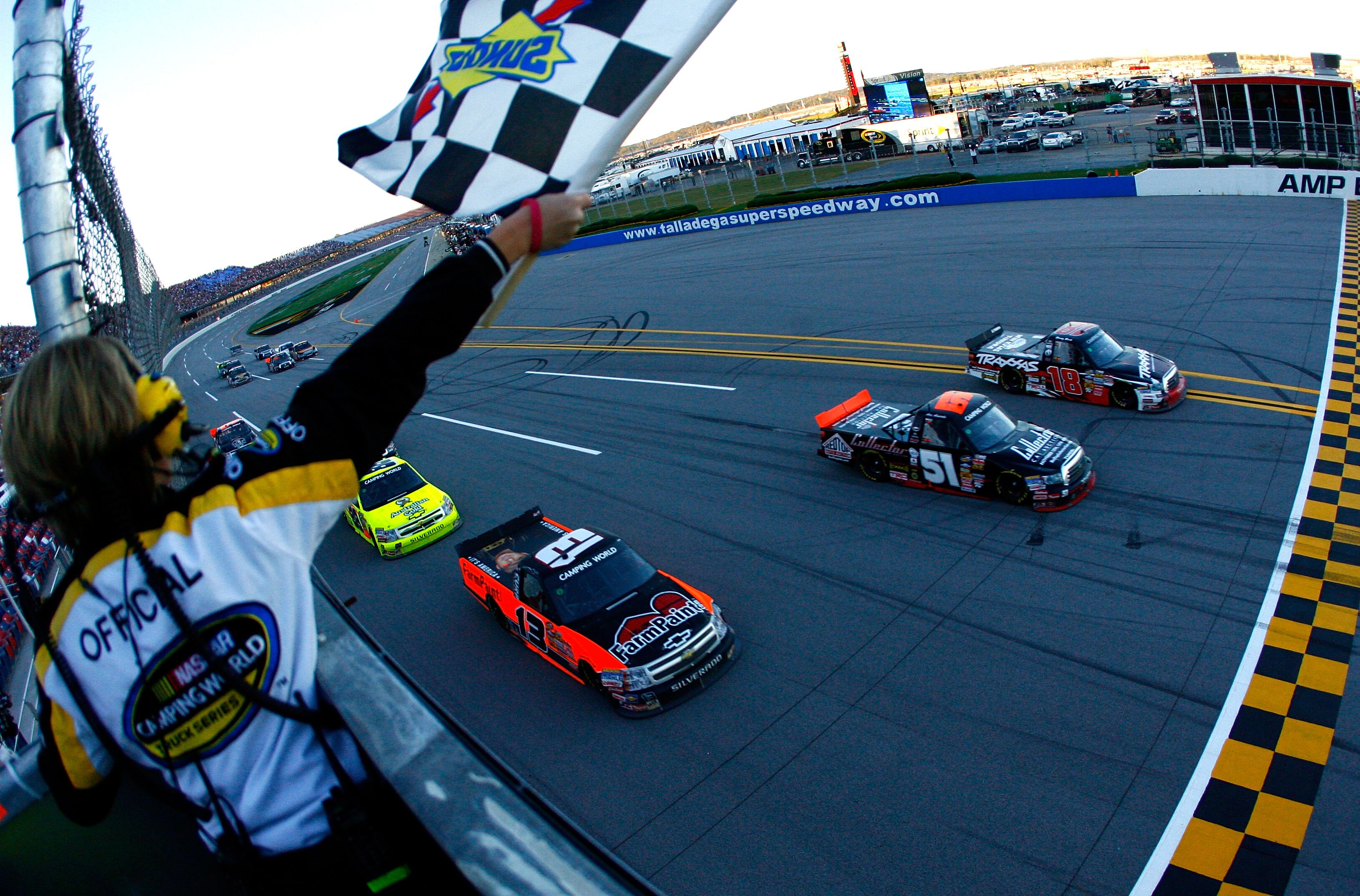 TALLADEGA, AL - OCTOBER 30:  Kyle Busch, driver of the #18 Tundra/TRAXXAS Toyota, crosses the finish line along side of Aric Almirola, driver of the #51 Billy Ballew Motorsports Toyota, and Johnny Sauter, driver of the #13 Farmpaint.com Chevrolet, to win 
