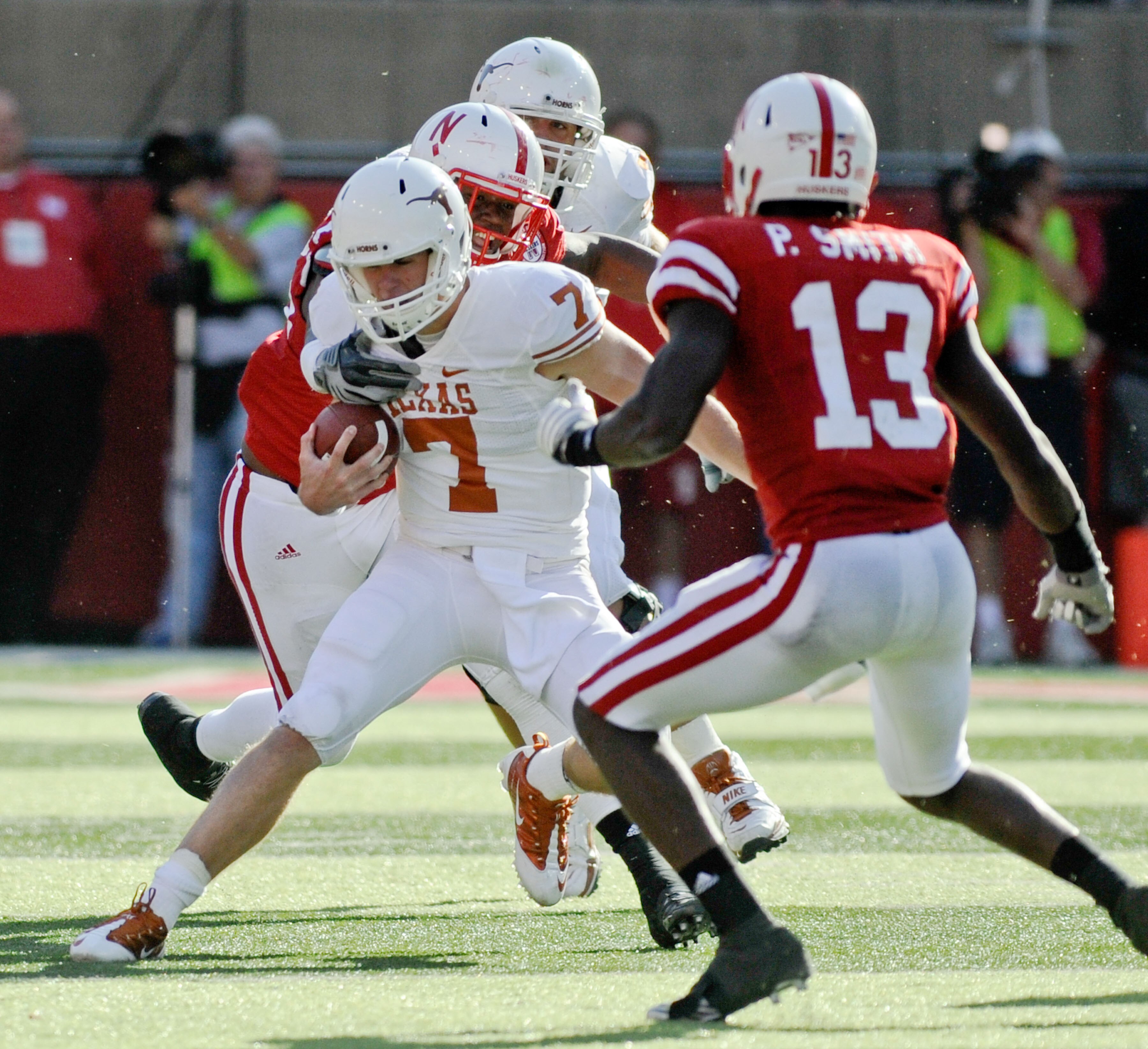LINCOLN, NE - OCTOBER 16: Quarterback Garrett Gilbert #7 of the Texas Longhorns tries to avoid safety P.J. Smith #13 and Nebraska Cornhuskers during second half action of their game at Memorial Stadium on October 16, 2010 in Lincoln, Nebraska. Texas Defea