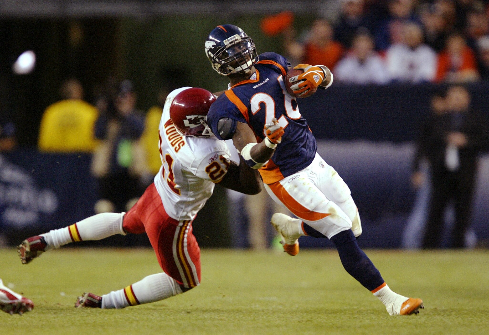 DENVER - DECEMBER 7:  Running back Clinton Portis #26 of the Denver Broncos pulls safety Jerome Woods #21 of the Kansas City Chiefs along for a ride December 7, 2003 at Invesco Field at Mile High in Denver, Colorado.  Portis ran for 218 yards and five tou