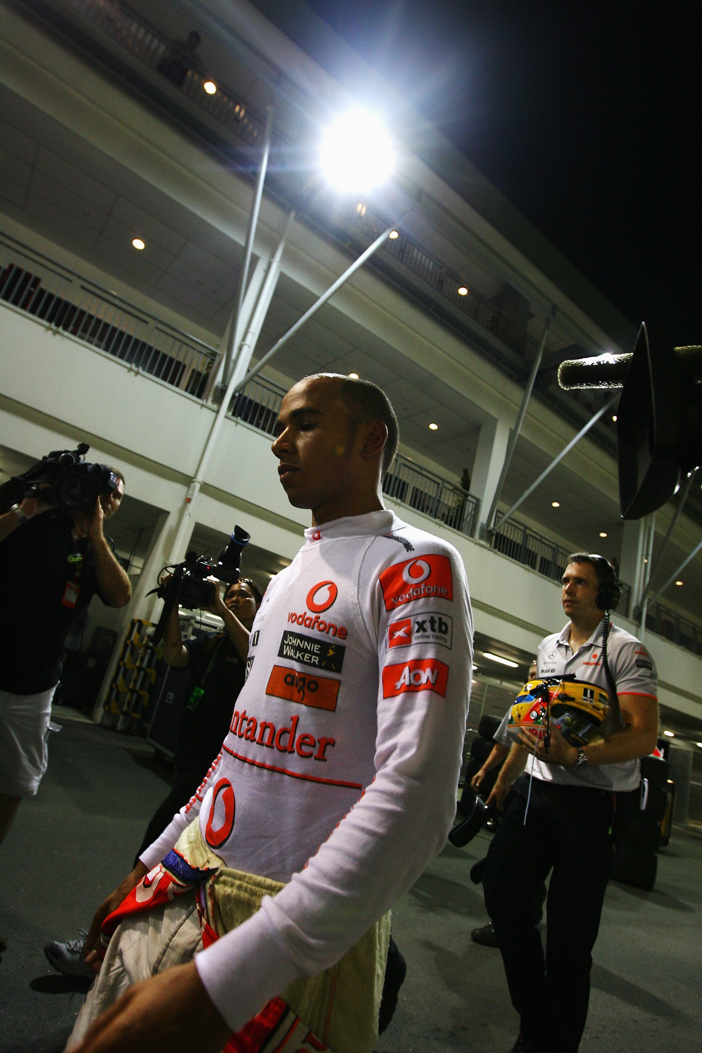 SINGAPORE - SEPTEMBER 26:  Lewis Hamilton of Great Britain and McLaren Mercedes is surrounded as he walks back to the paddock after retiring early following a coming together with Mark Webber of Australia and Red Bull Racing during the Singapore Formula O